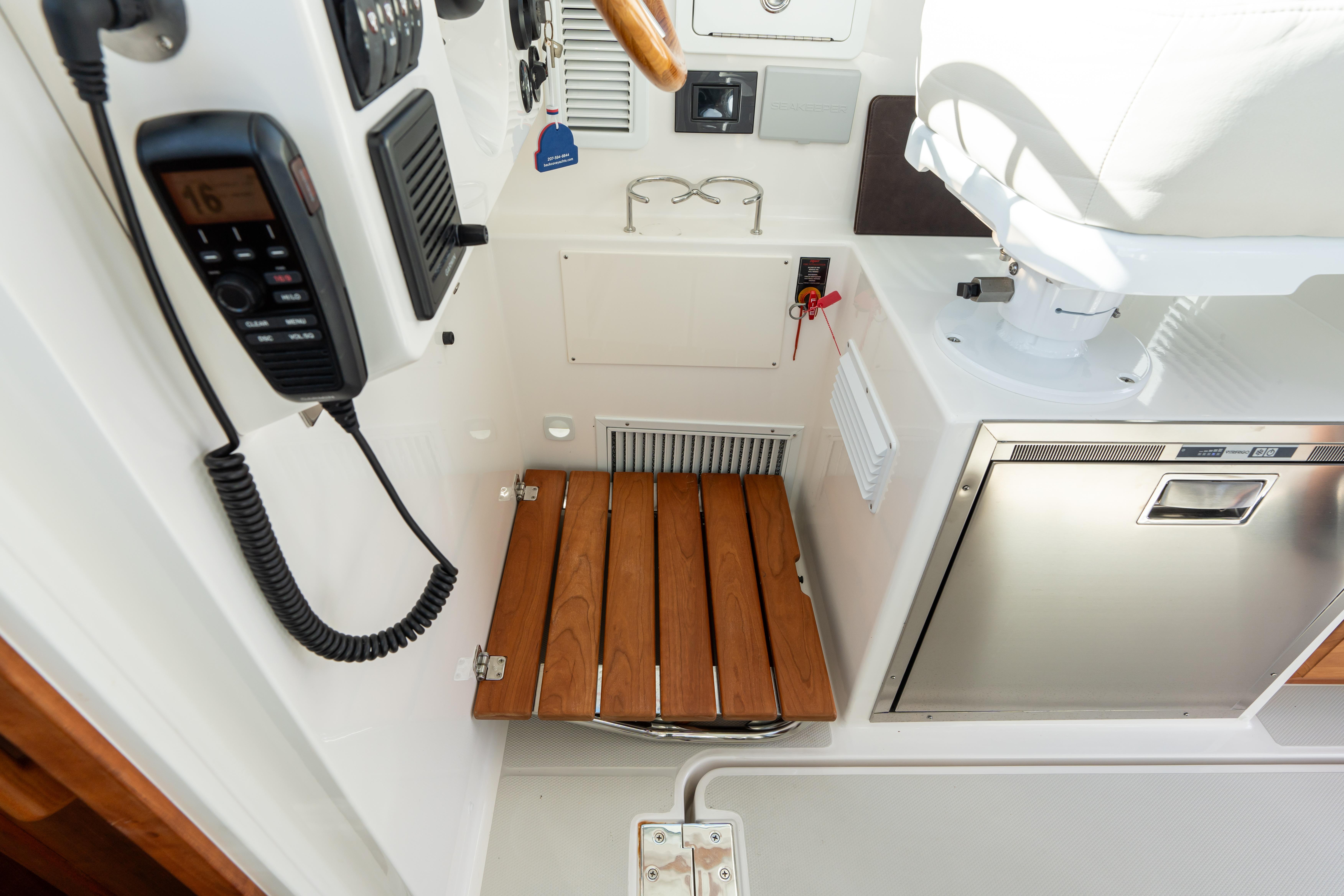 2023 Back Cove 340 boat interior with wooden fold up step, control panel, and stainless steel appliance.