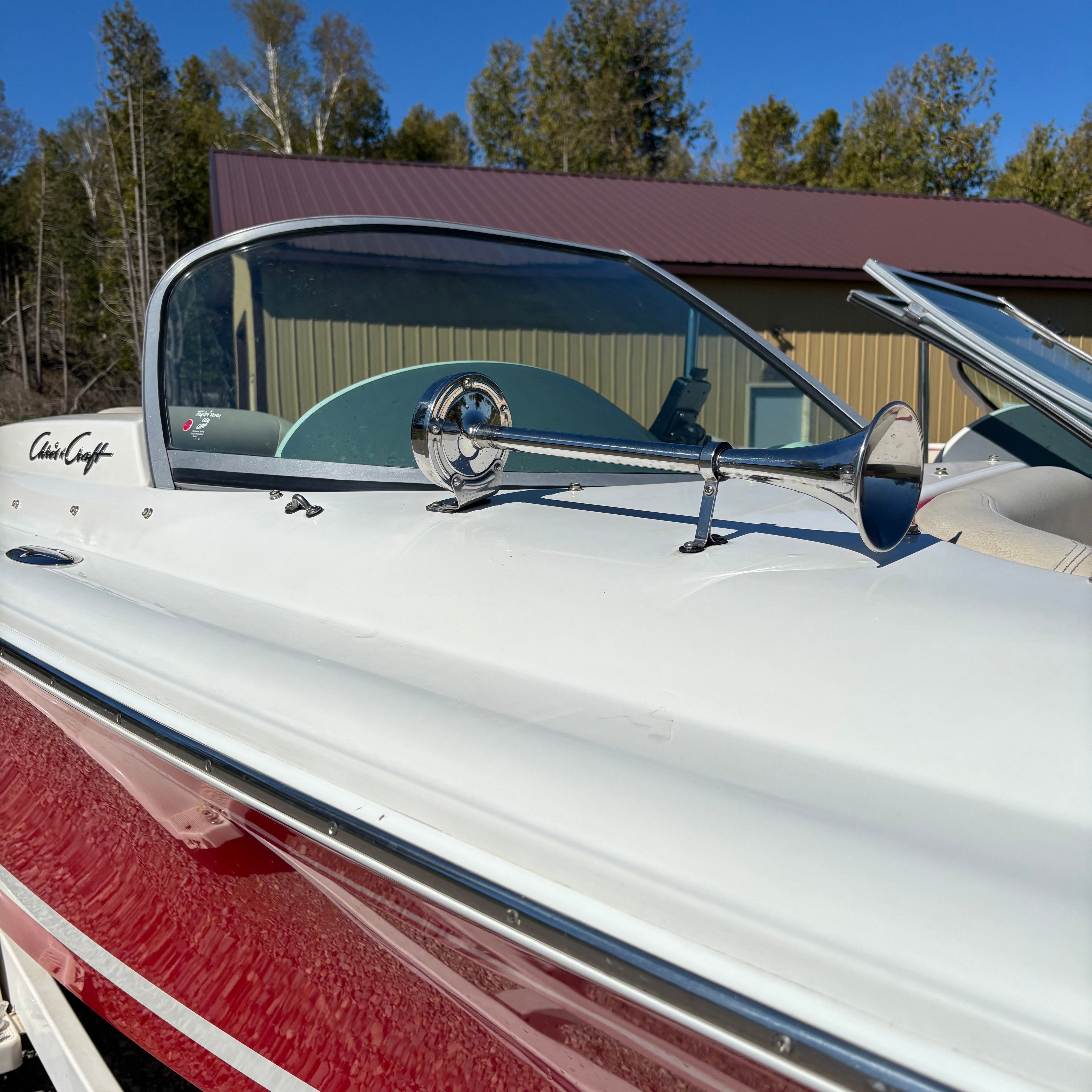 A 2003 Chris-Craft Launch 22 boat with a red hull and chrome horn.