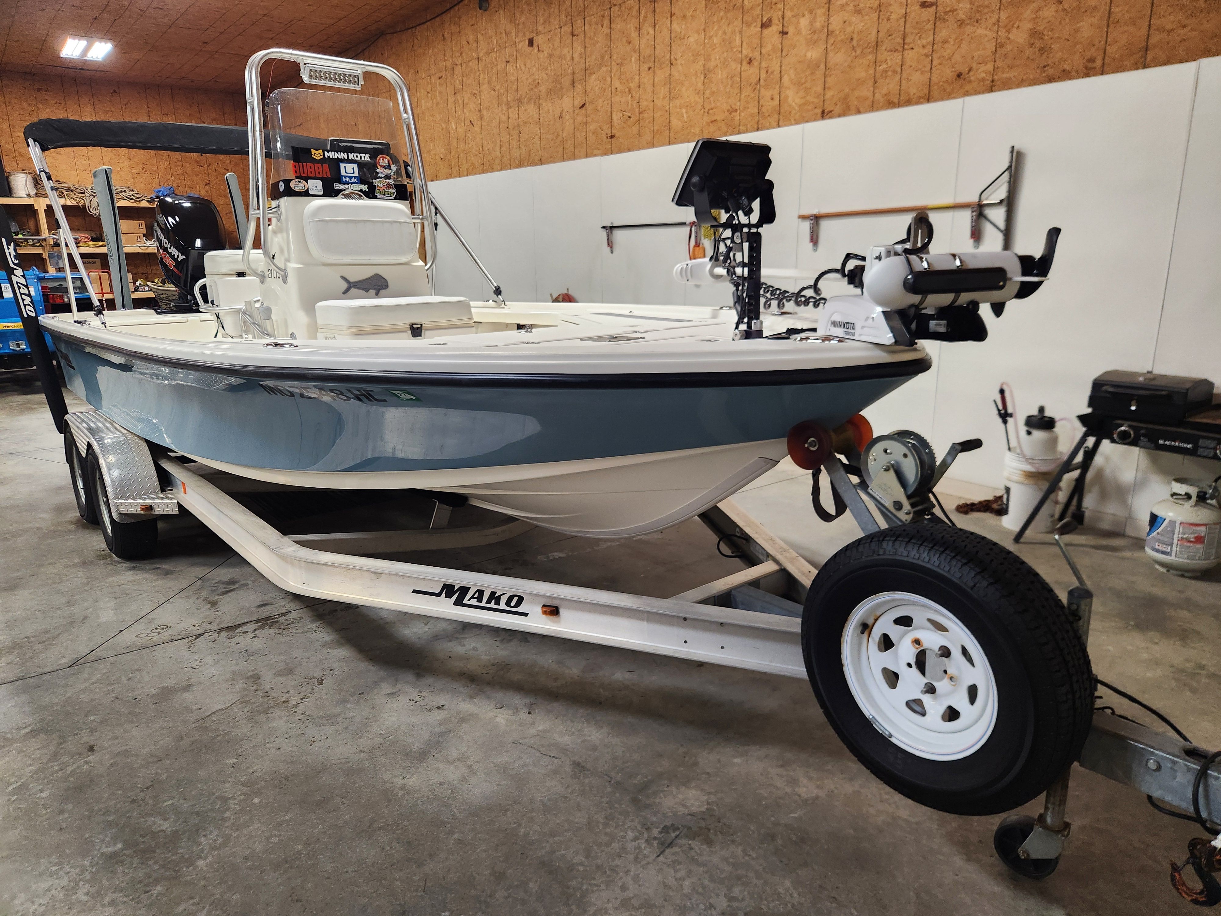 A 2014 Mako 21 LTS boat on a trailer in a warehouse.