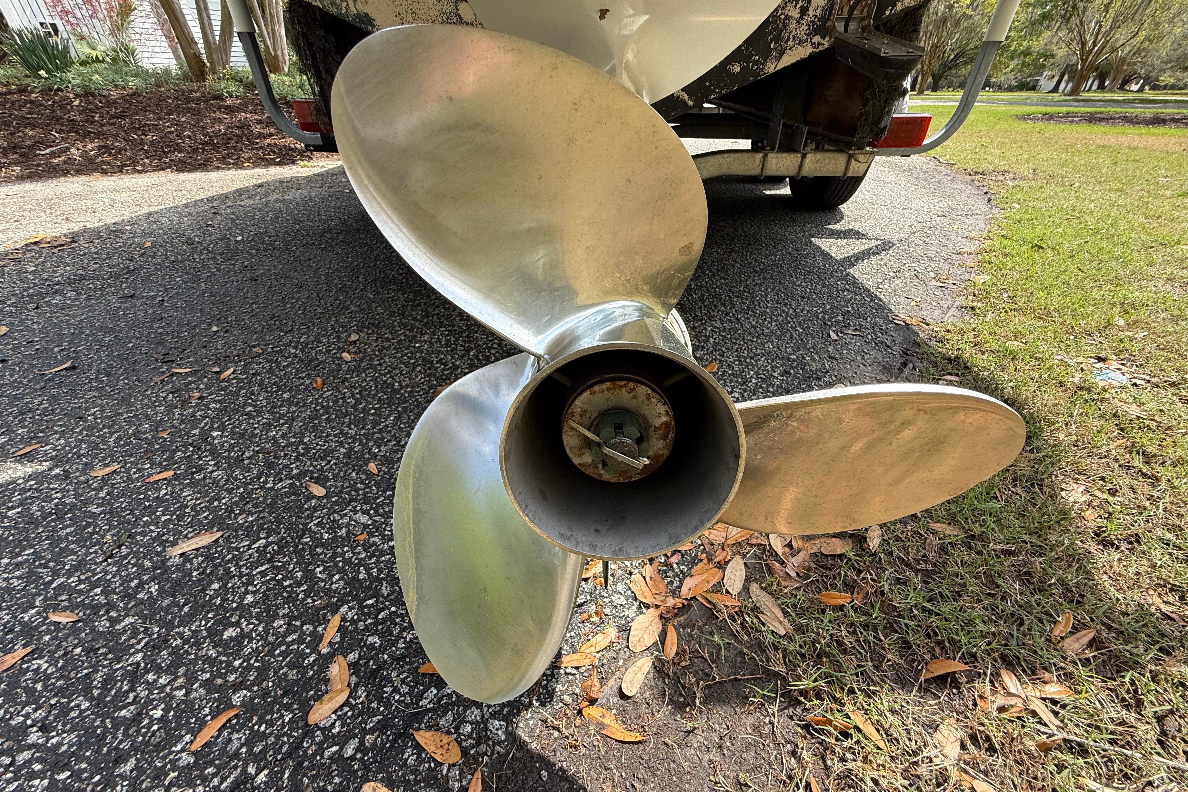 Propeller of a 1997 Regulator 23 boat on a trailer, parked on a driveway.