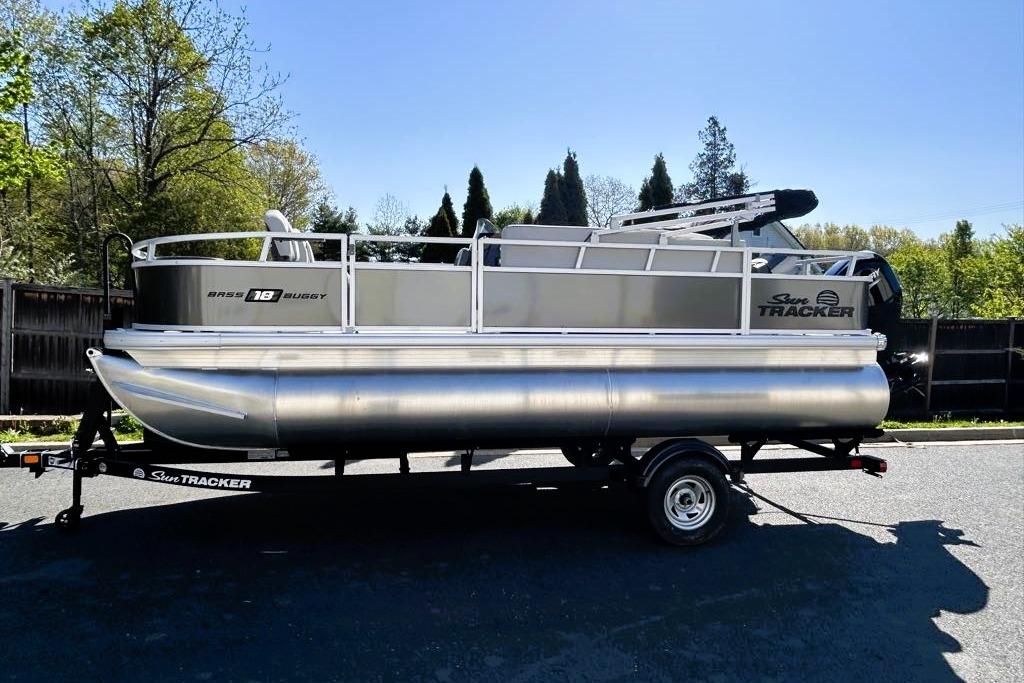 2026 Sun Tracker Bass Buggy 18 DLX pontoon boat on trailer, parked outdoors.