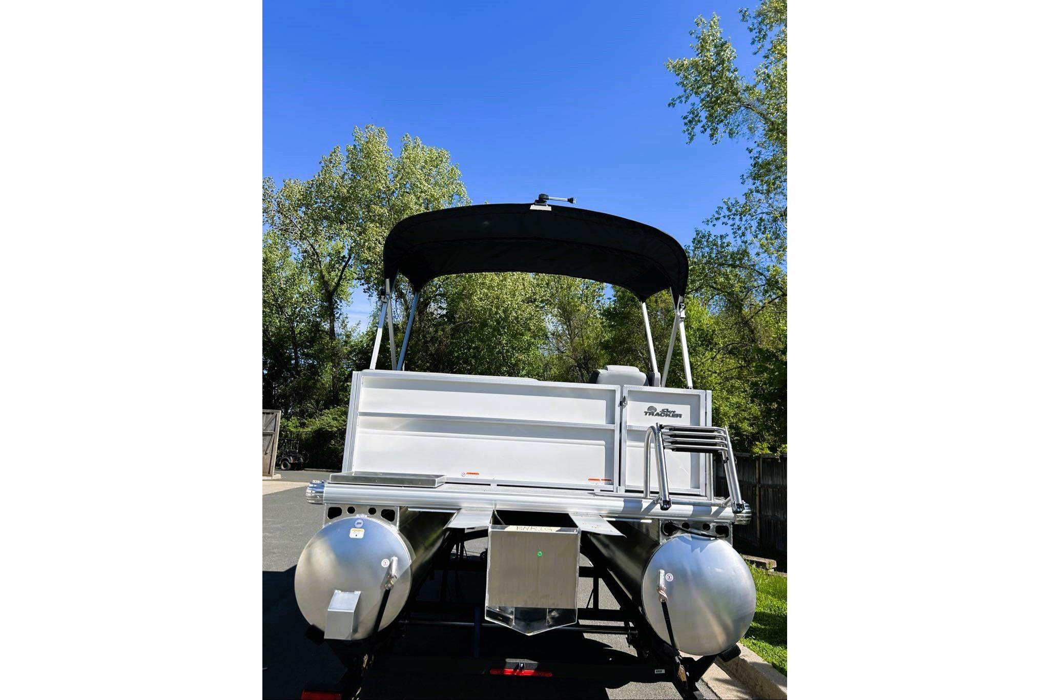 2026 Sun Tracker Party Barge 16 DLX pontoon boat with canopy, parked outdoors.