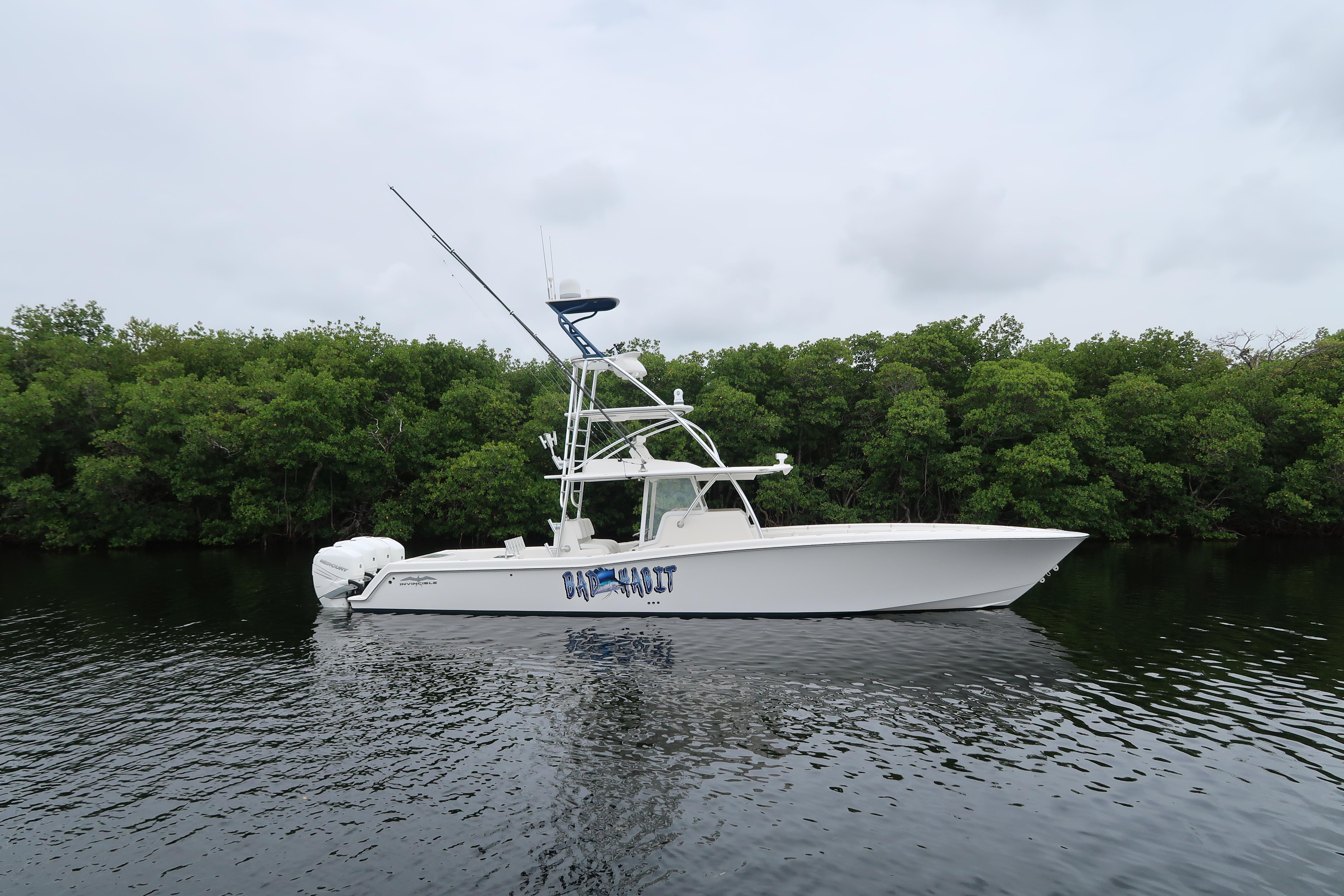 2016 Invincible 42 Open Fisherman boat on calm water with lush green background.