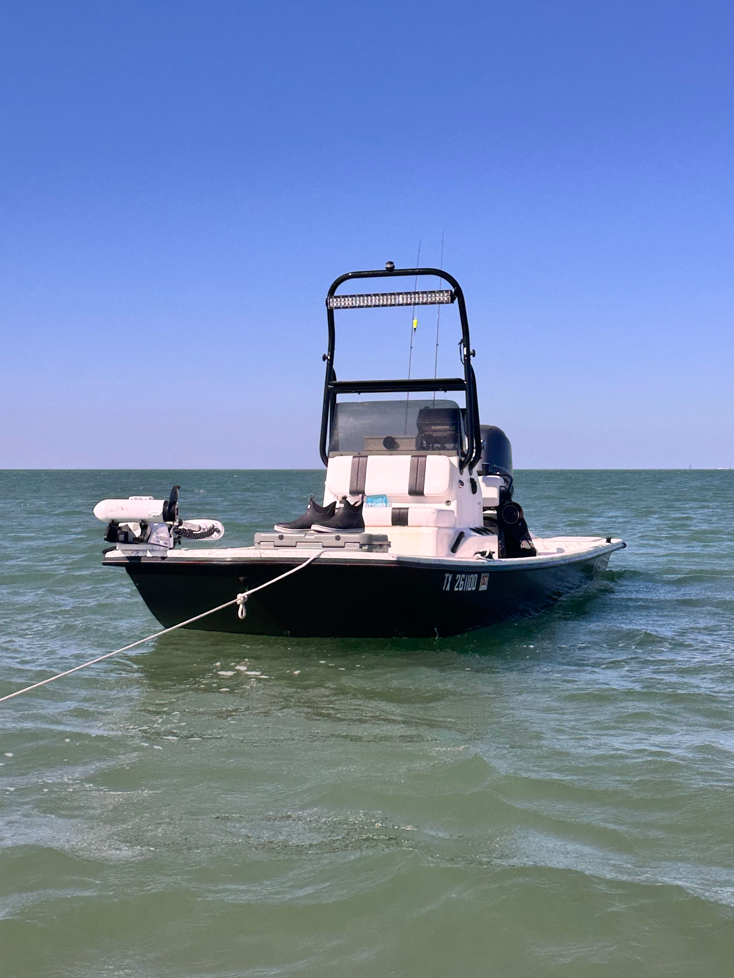A 2015 Majek Redfish Line boat floats on calm water under a clear sky.