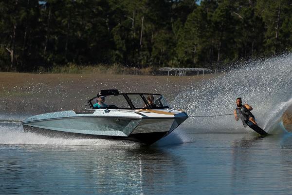 Manufacturer Provided Image: 2024 Nautique Ski boat towing a water skier on a calm lake.