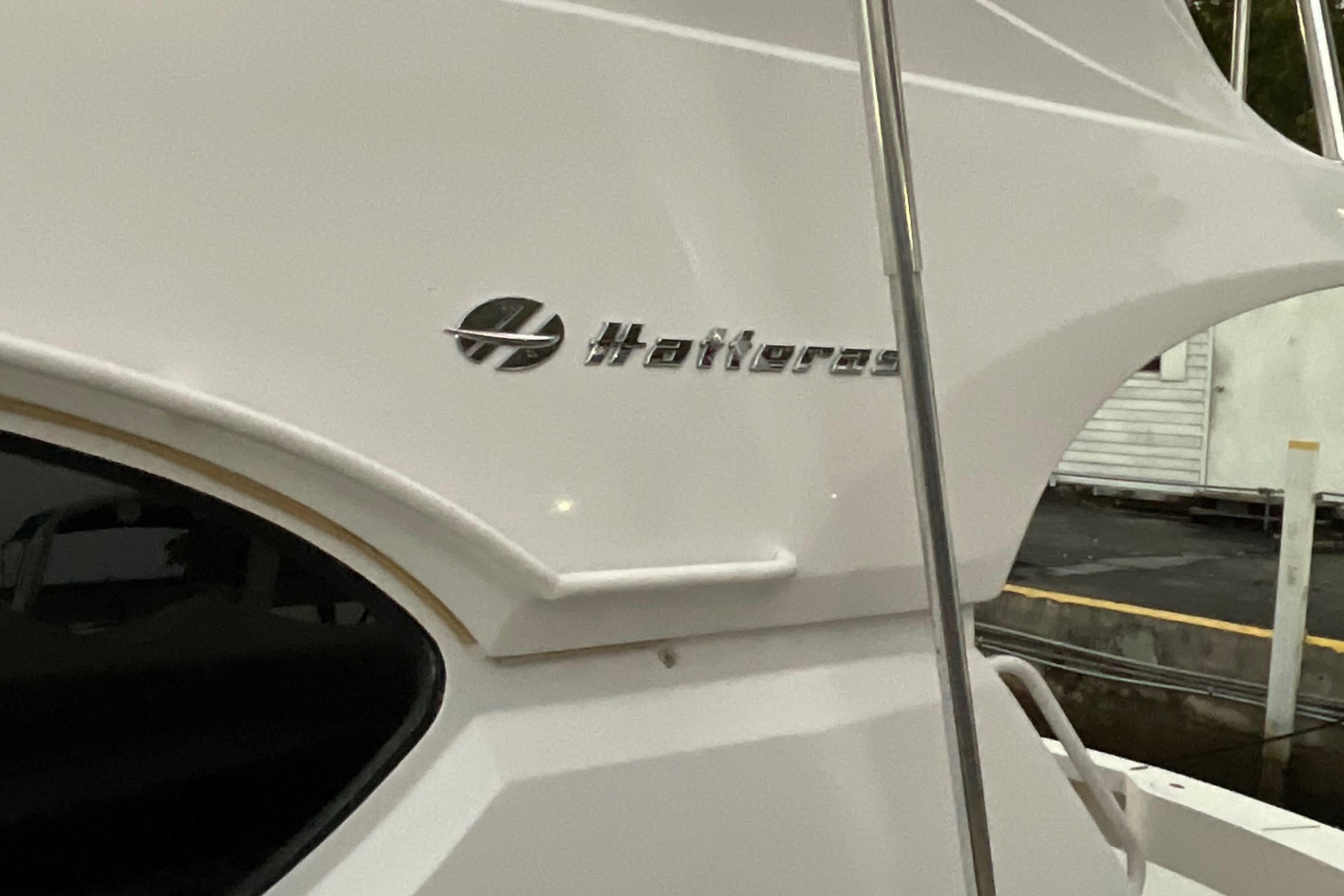 2008 Hatteras 77 Convertible yacht, sleek white exterior with logo detail.