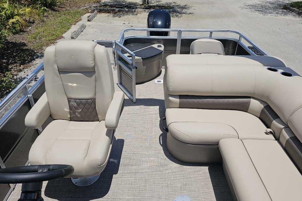 2025 Sun Tracker SportFish 20 DLX pontoon boat with beige seating and steering wheel.
