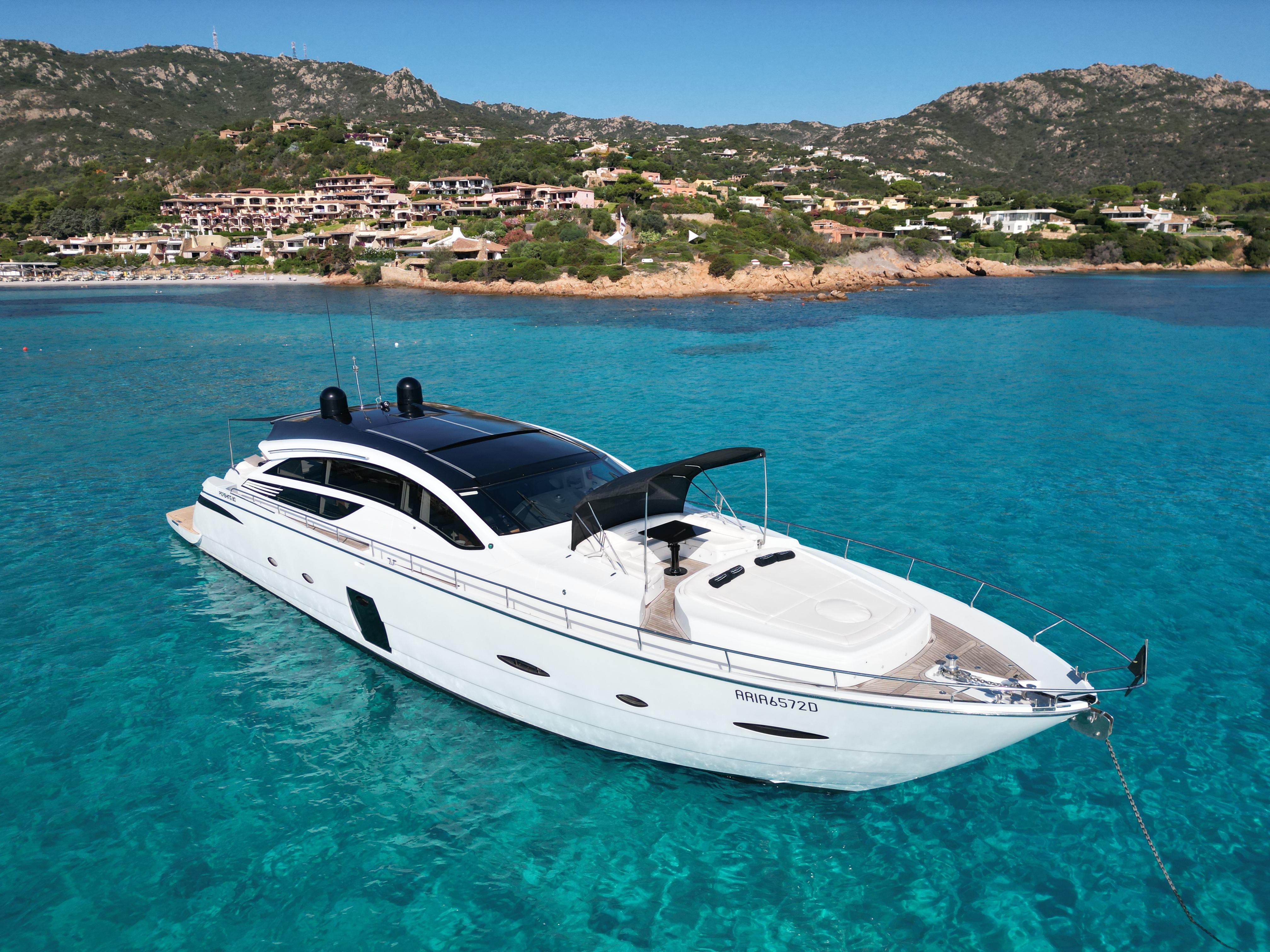 Luxurious 2008 Pershing 80 yacht anchored in clear turquoise waters near a scenic coastline.