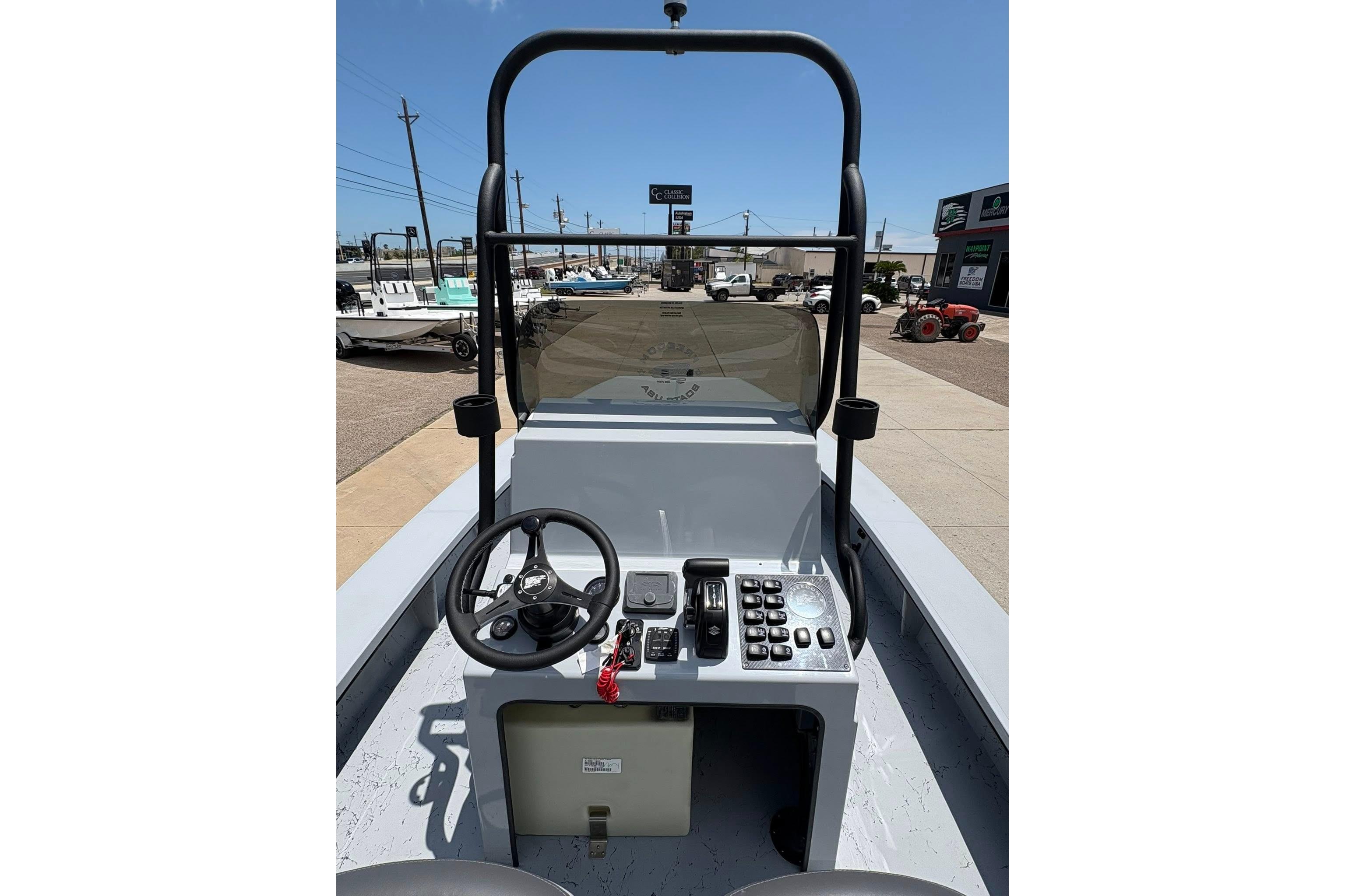 2026 Freedom Boats 23' Warrior console with steering wheel and controls, docked outdoors.