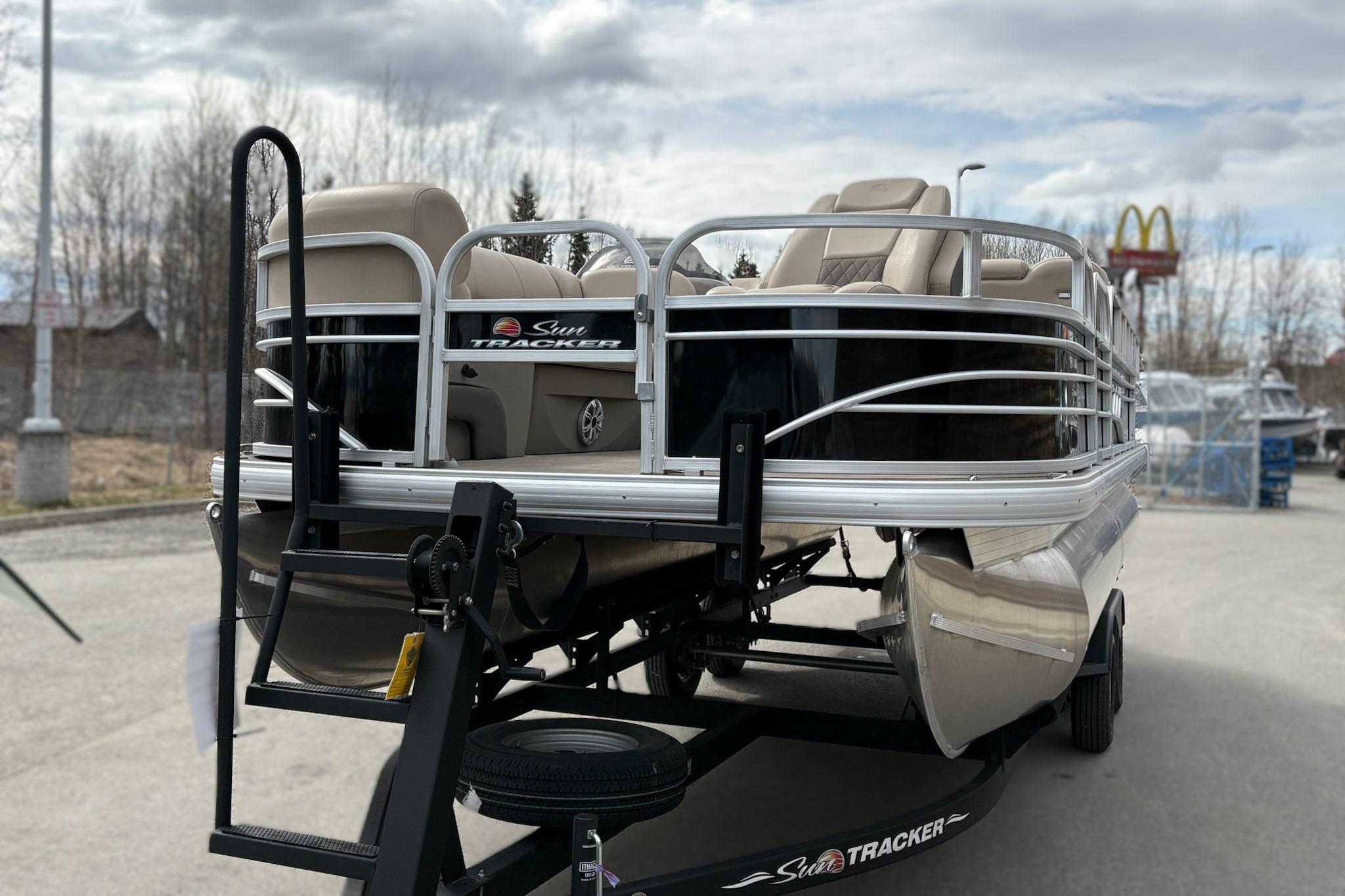 2023 Sun Tracker SportFish 20 DLX pontoon boat on trailer, parked outdoors.
