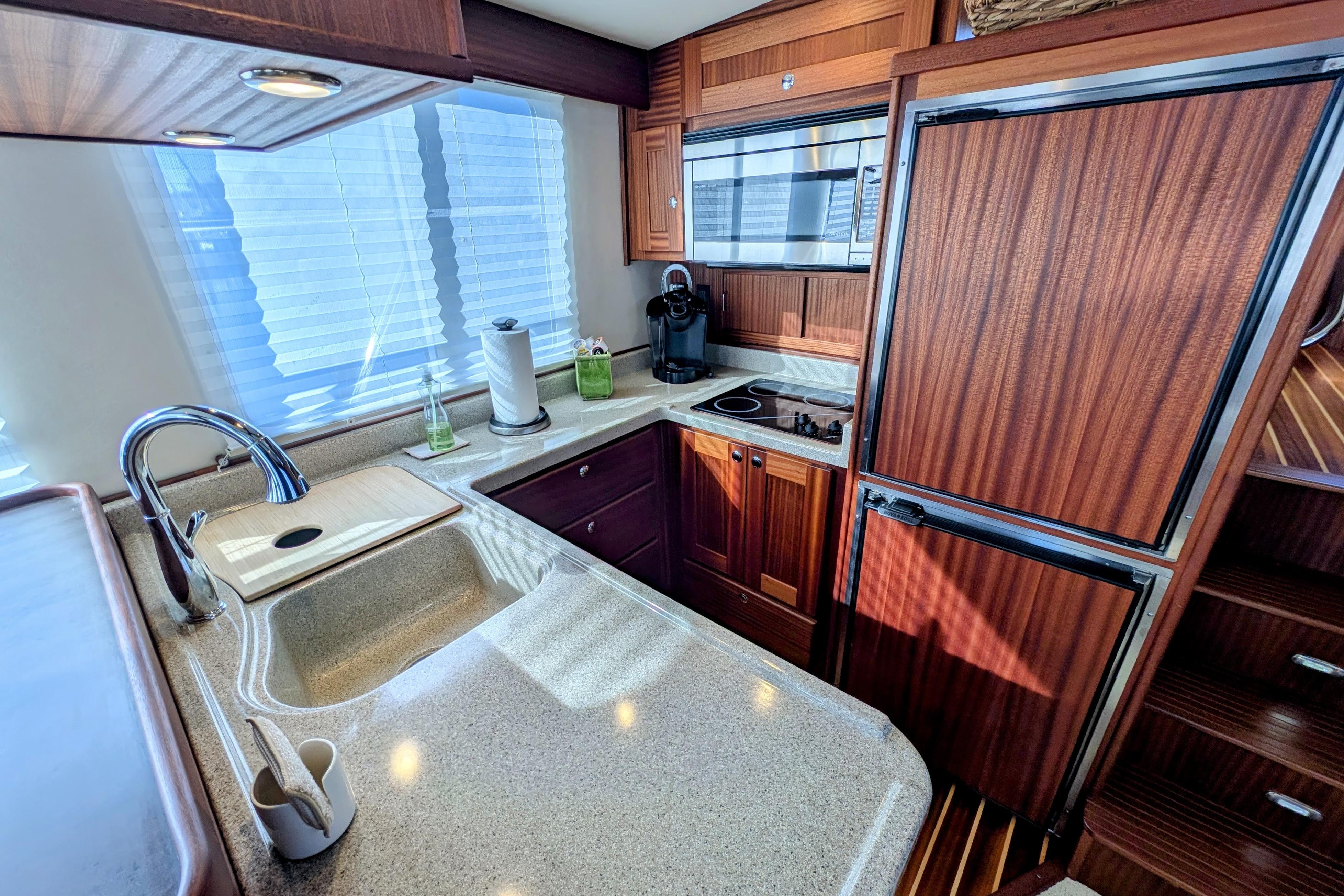 Luxurious 2015 American Tug 435 kitchen with modern appliances and elegant wood cabinetry.