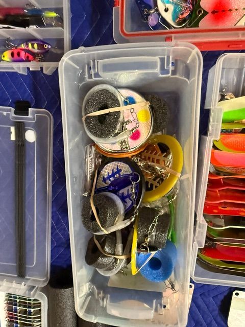 A box containing various fishing lures and accessories, including colorful floats and hooks.