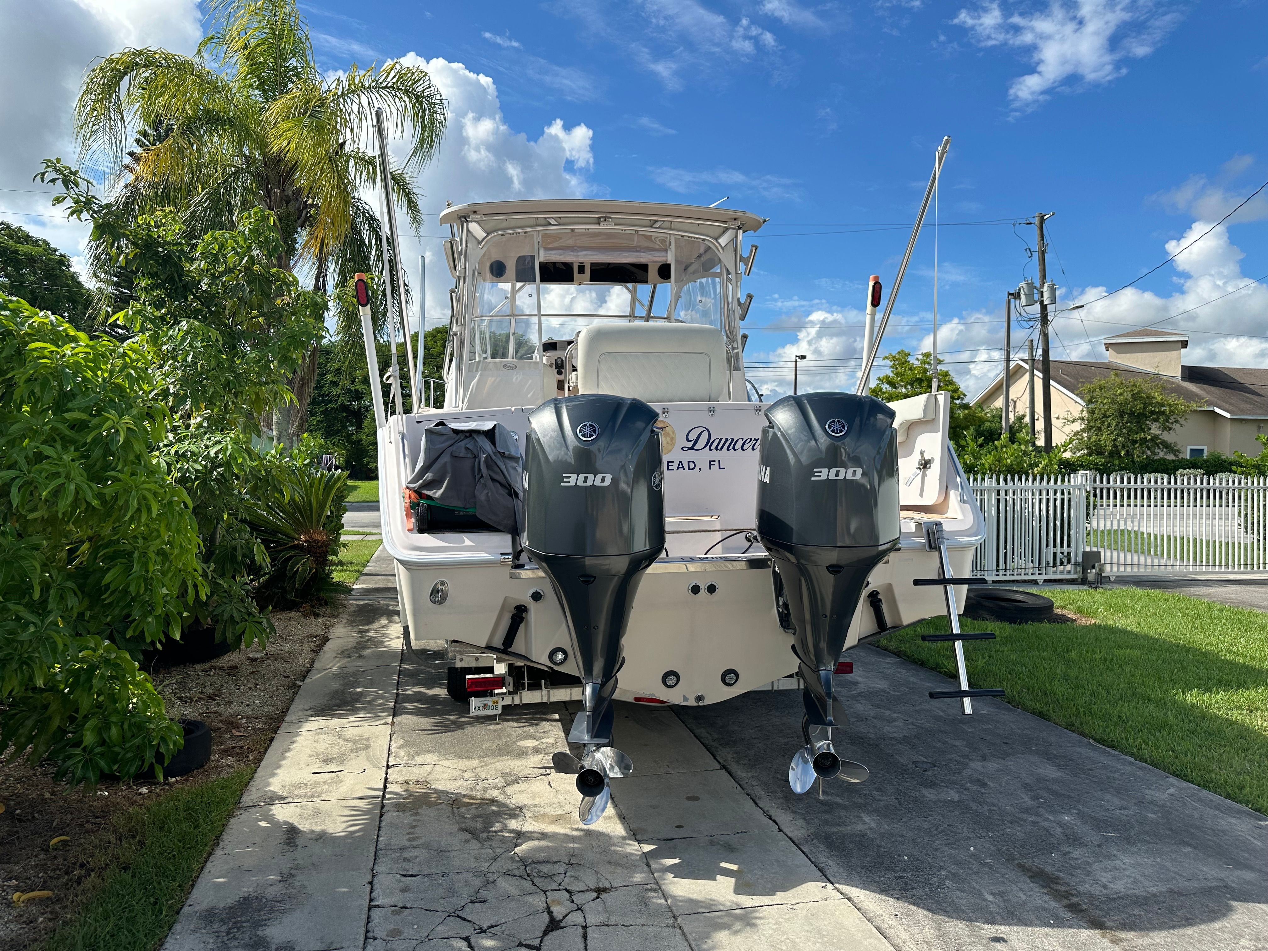 A 2003 Grady-White Express 330 boat on a paved driveway, surrounded by palm trees.