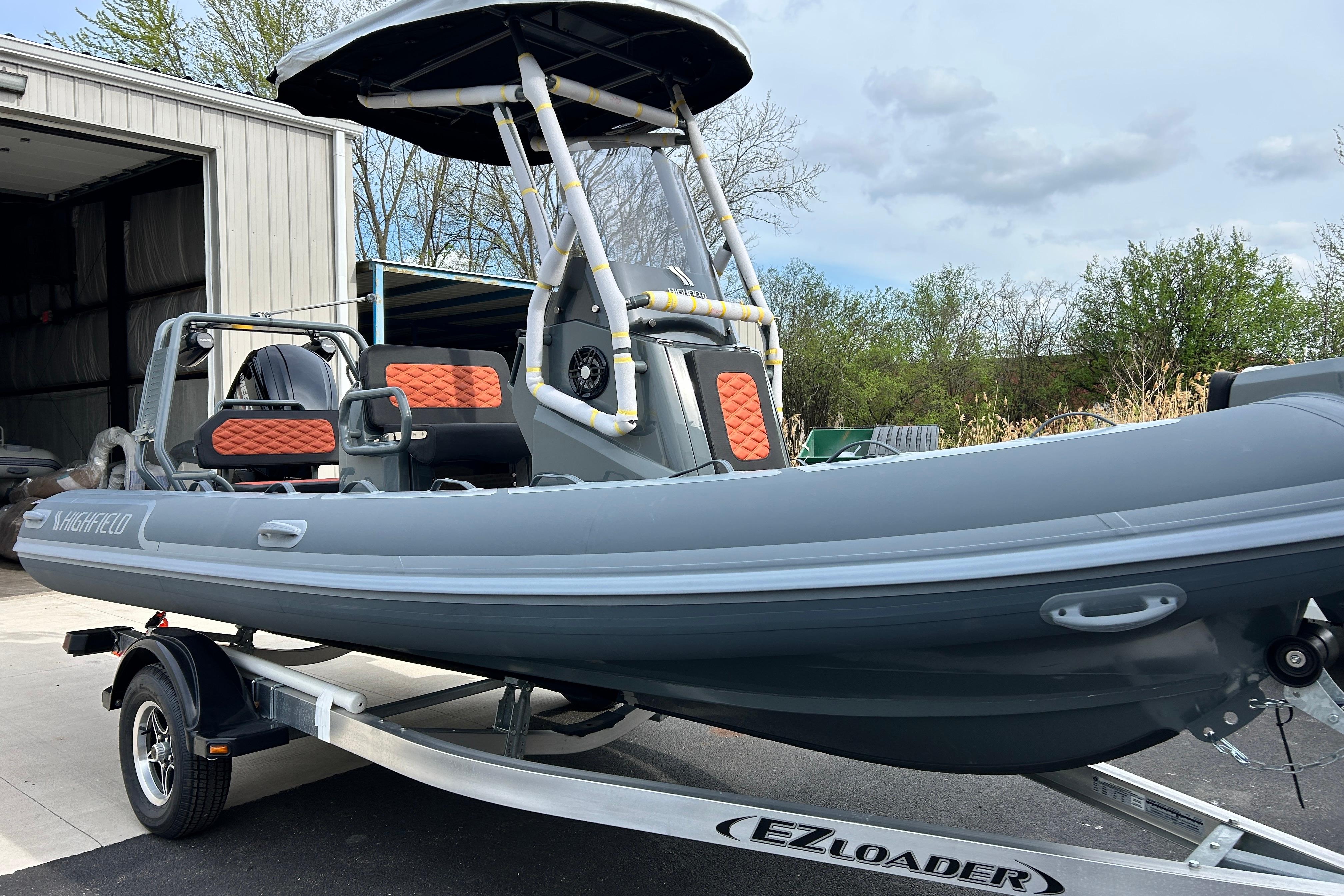 2026 Highfield Sport 560 boat on trailer, featuring sleek design and orange seating accents.