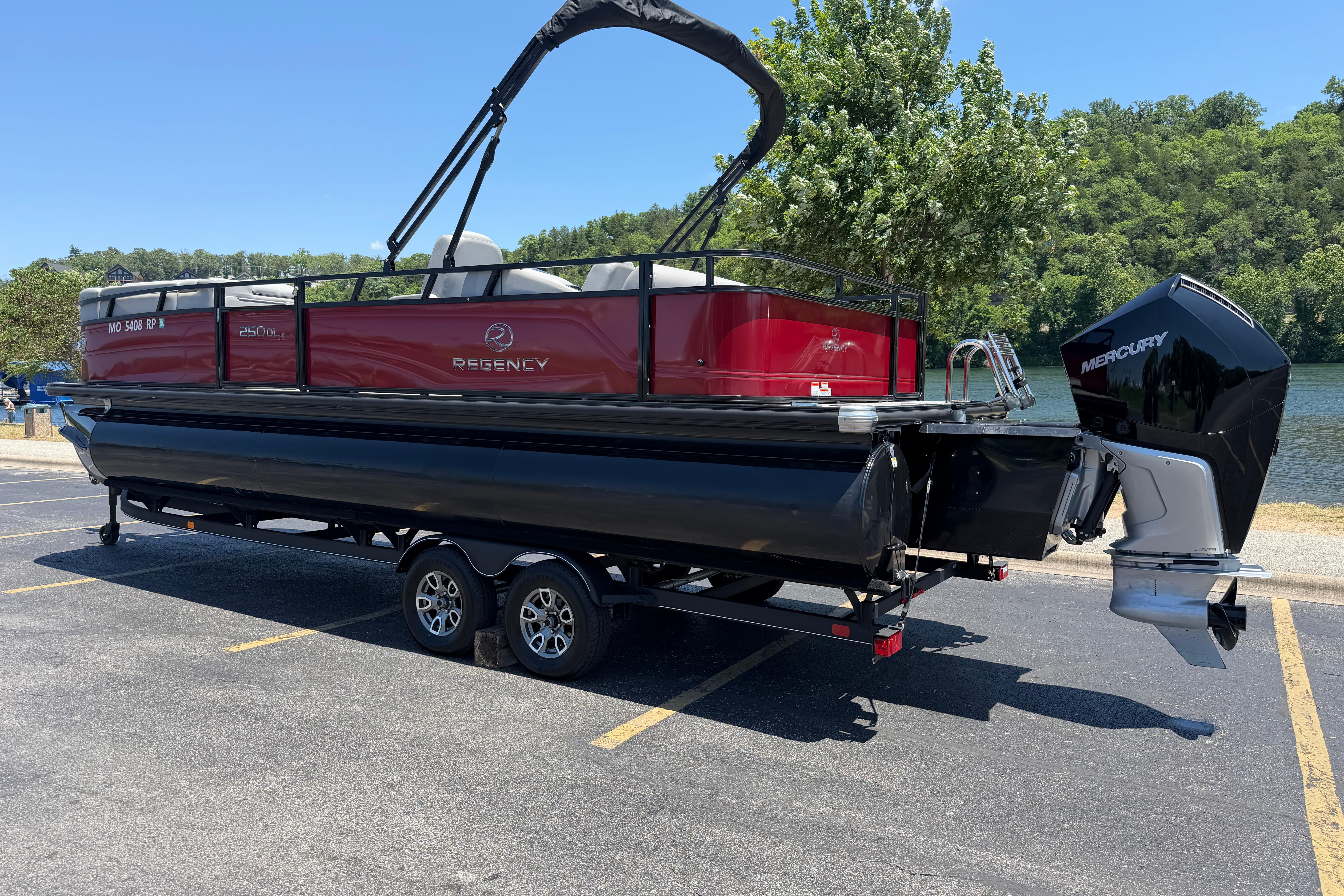 2024 Regency R250DL3 pontoon boat on trailer, parked near a scenic lake.