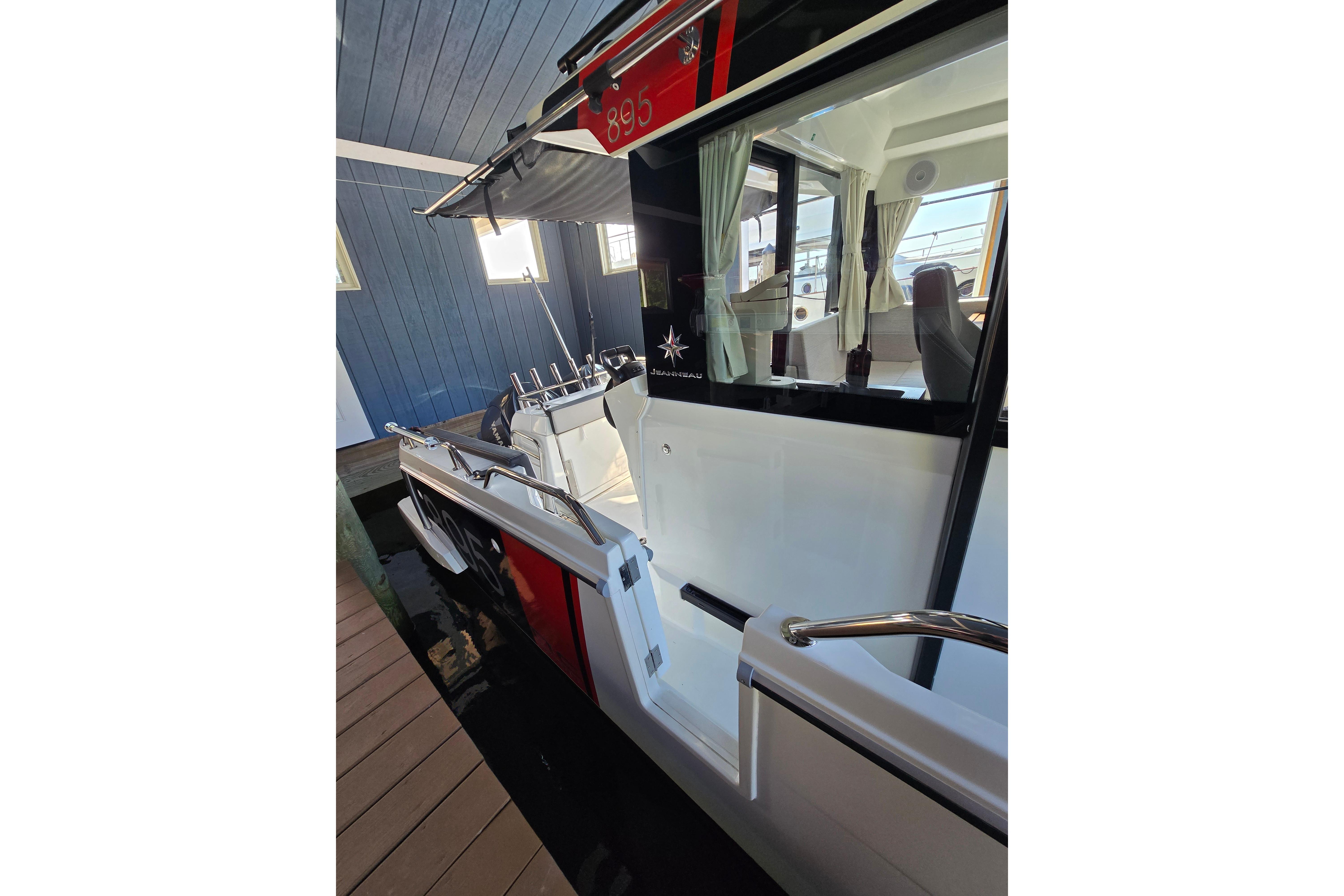 The image shows a modern boat docked, featuring a sleek white and red design.
