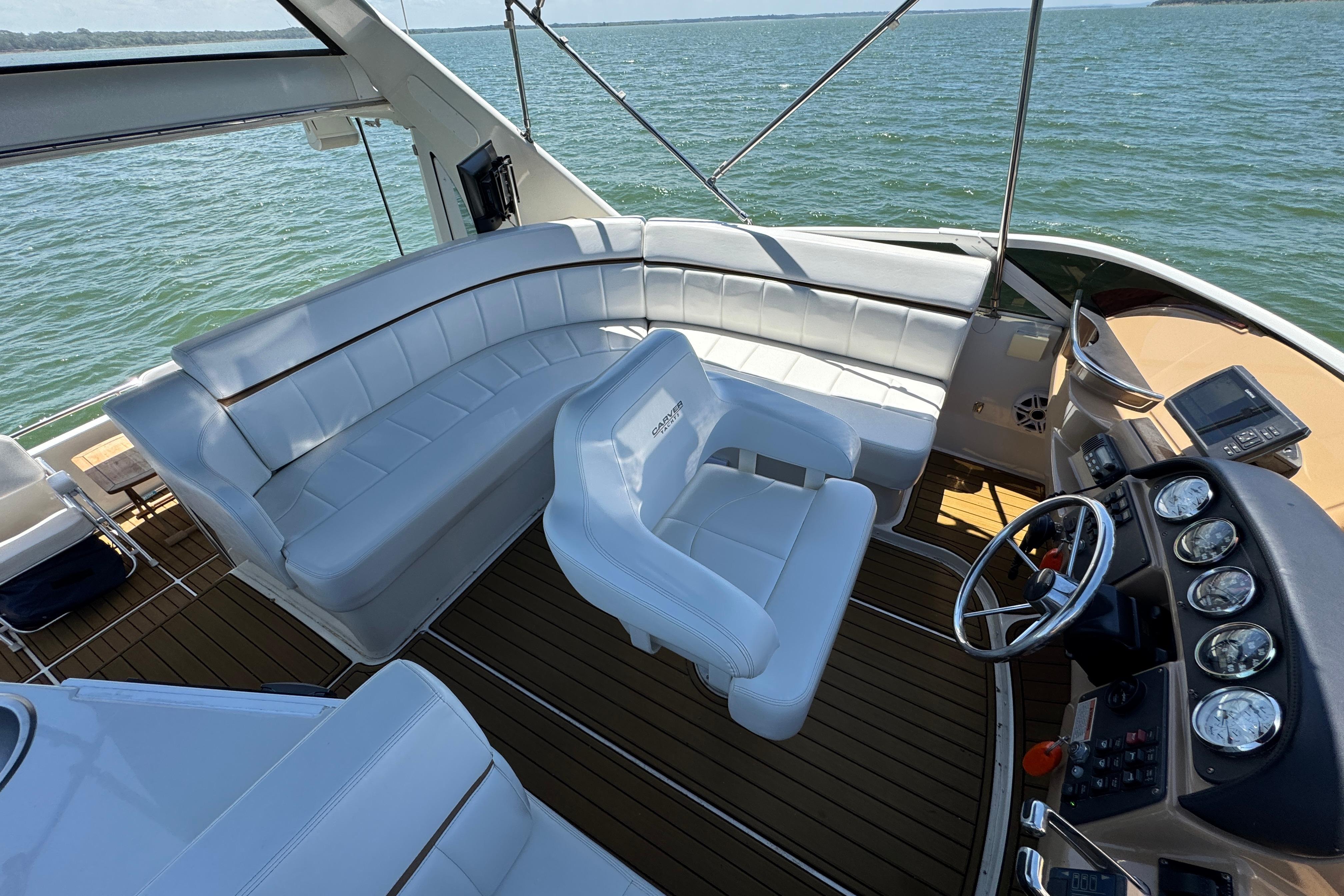 2002 Carver 396 Motor Yacht cockpit with white seating and steering, overlooking the water.