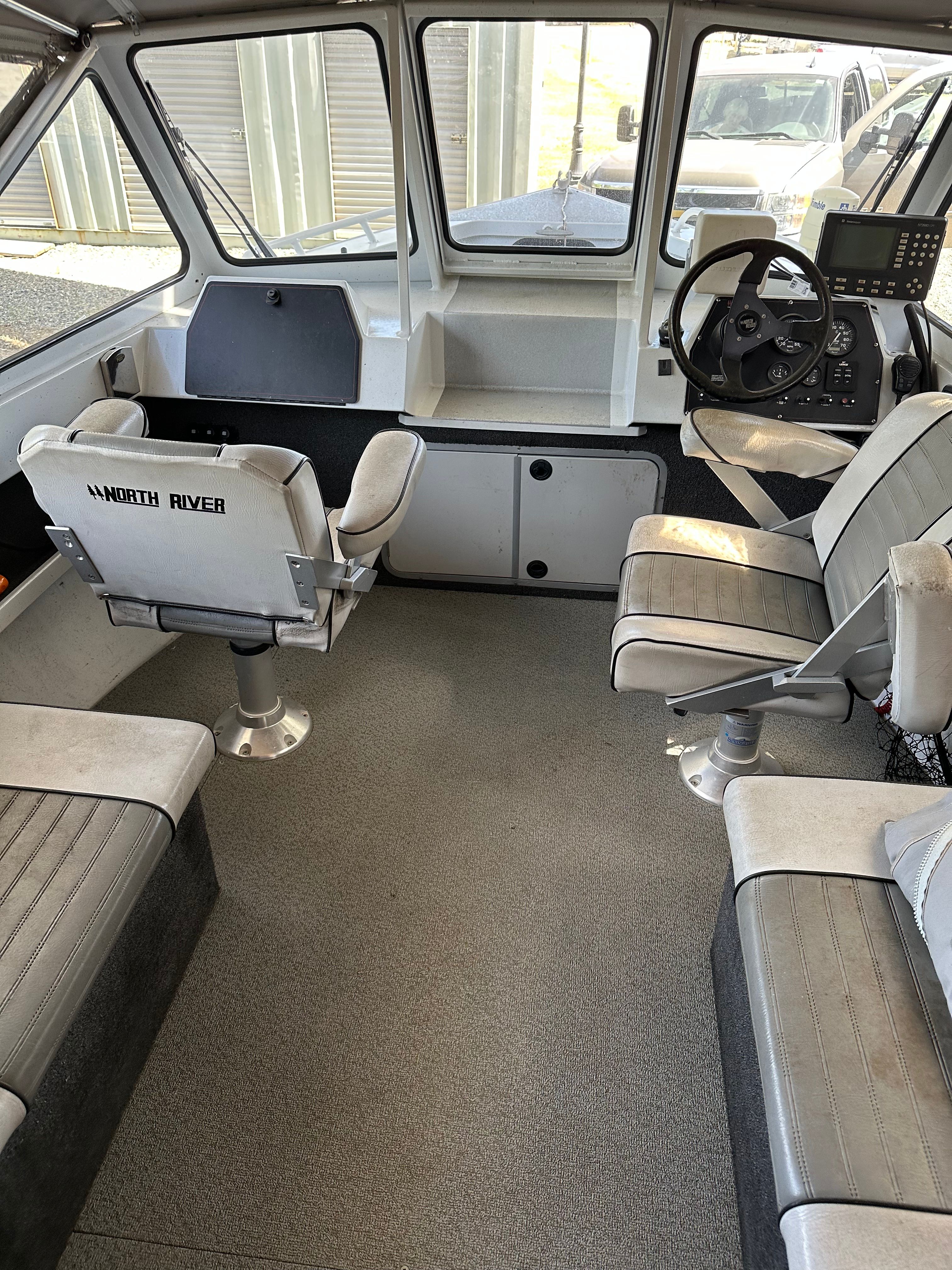 Interior of a 2006 North River aluminum boat with two seats and a helm station.
