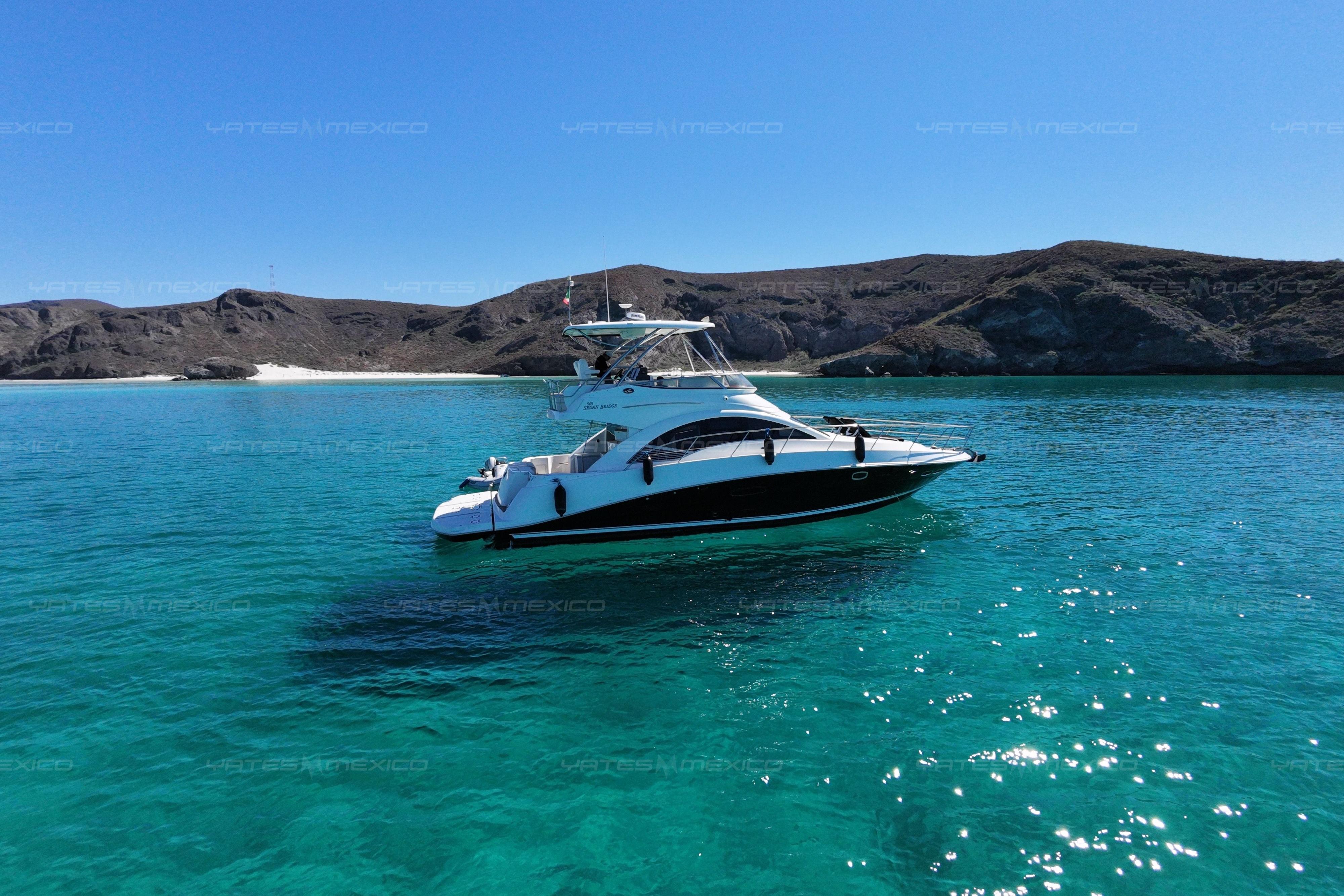 2008 Sea Ray 480 Sedan Bridge yacht on clear turquoise water near rocky coastline.