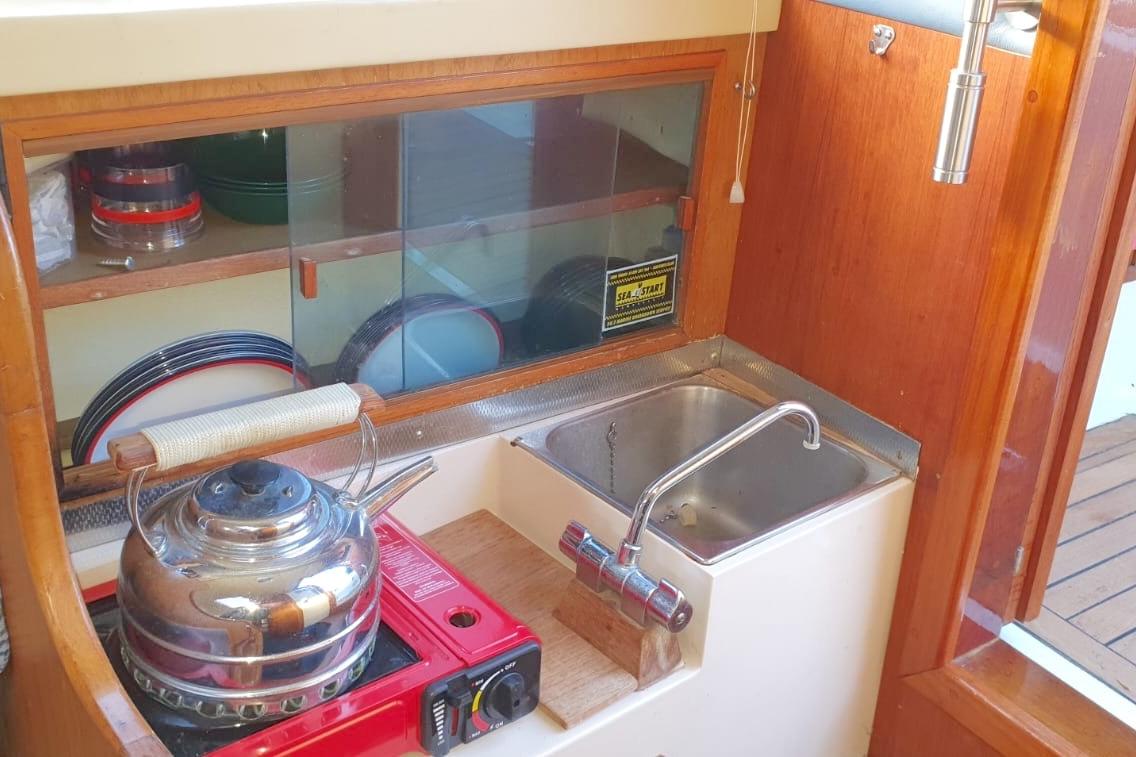 Compact kitchen area in a 1989 Fairey Spearfish MKIII boat with sink and stove.