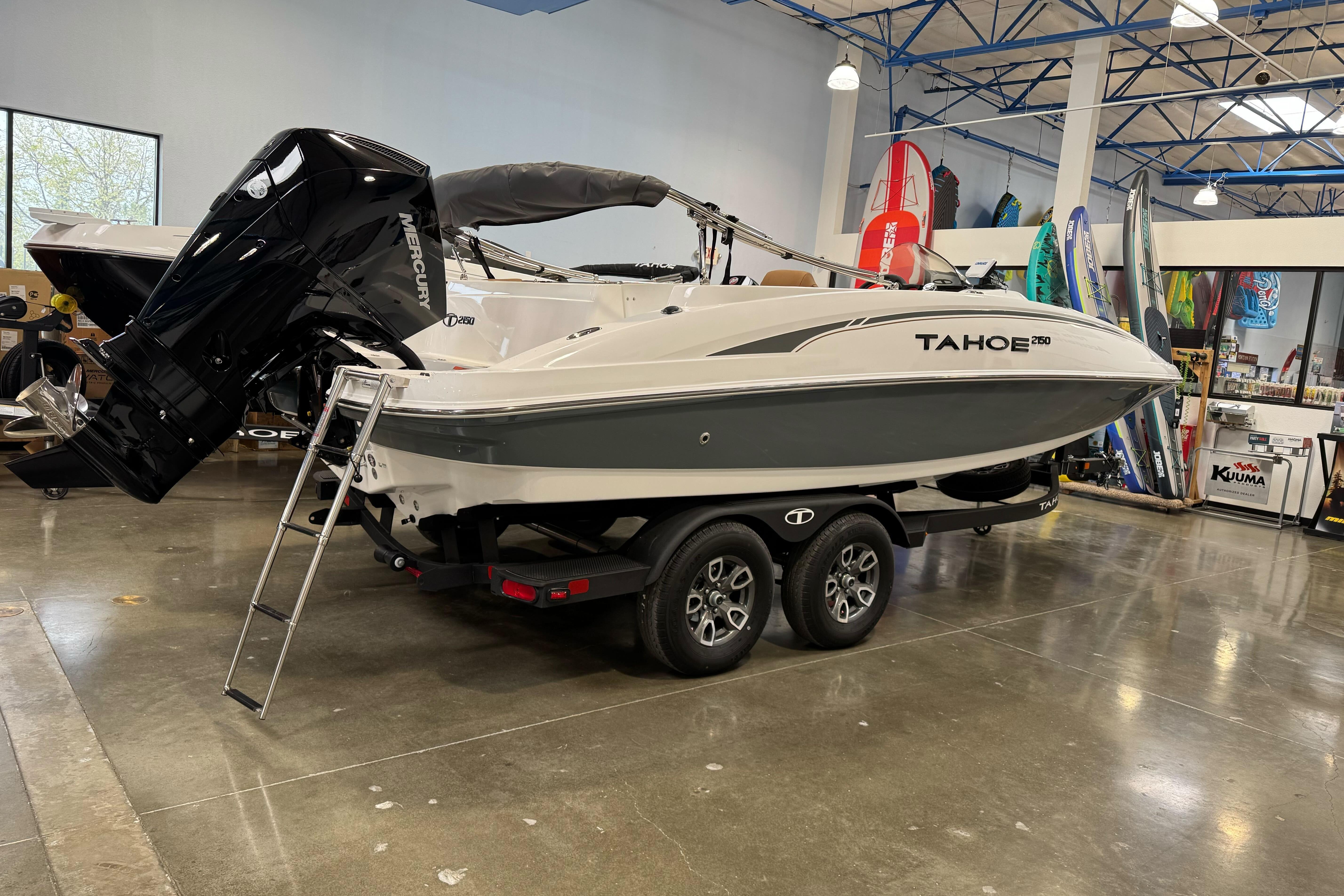 2026 Tahoe 2150 boat on trailer in showroom with Mercury outboard motor.
