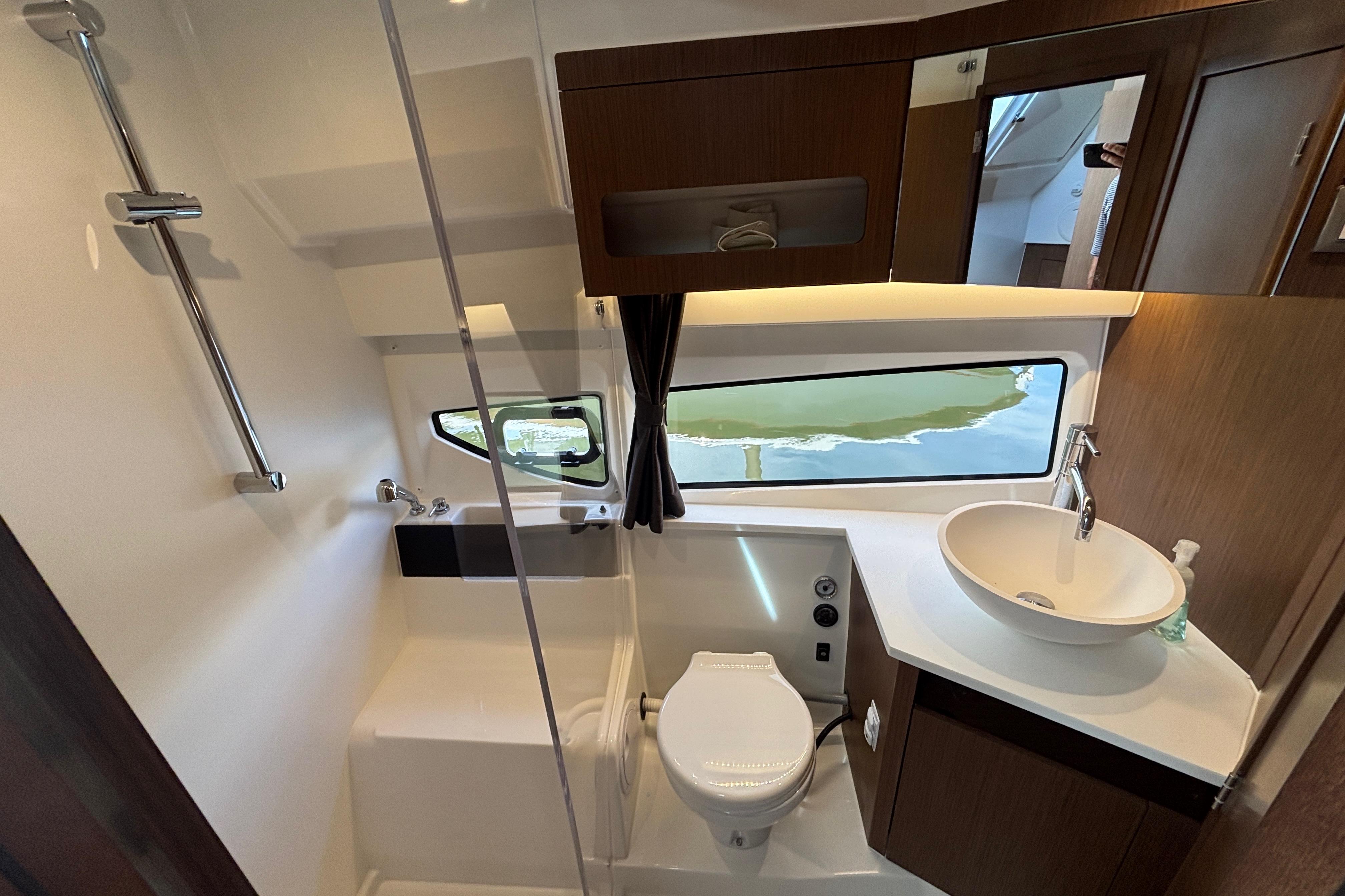 2024 Beneteau Antares 11 bathroom with modern fixtures, window view, and elegant wood accents.