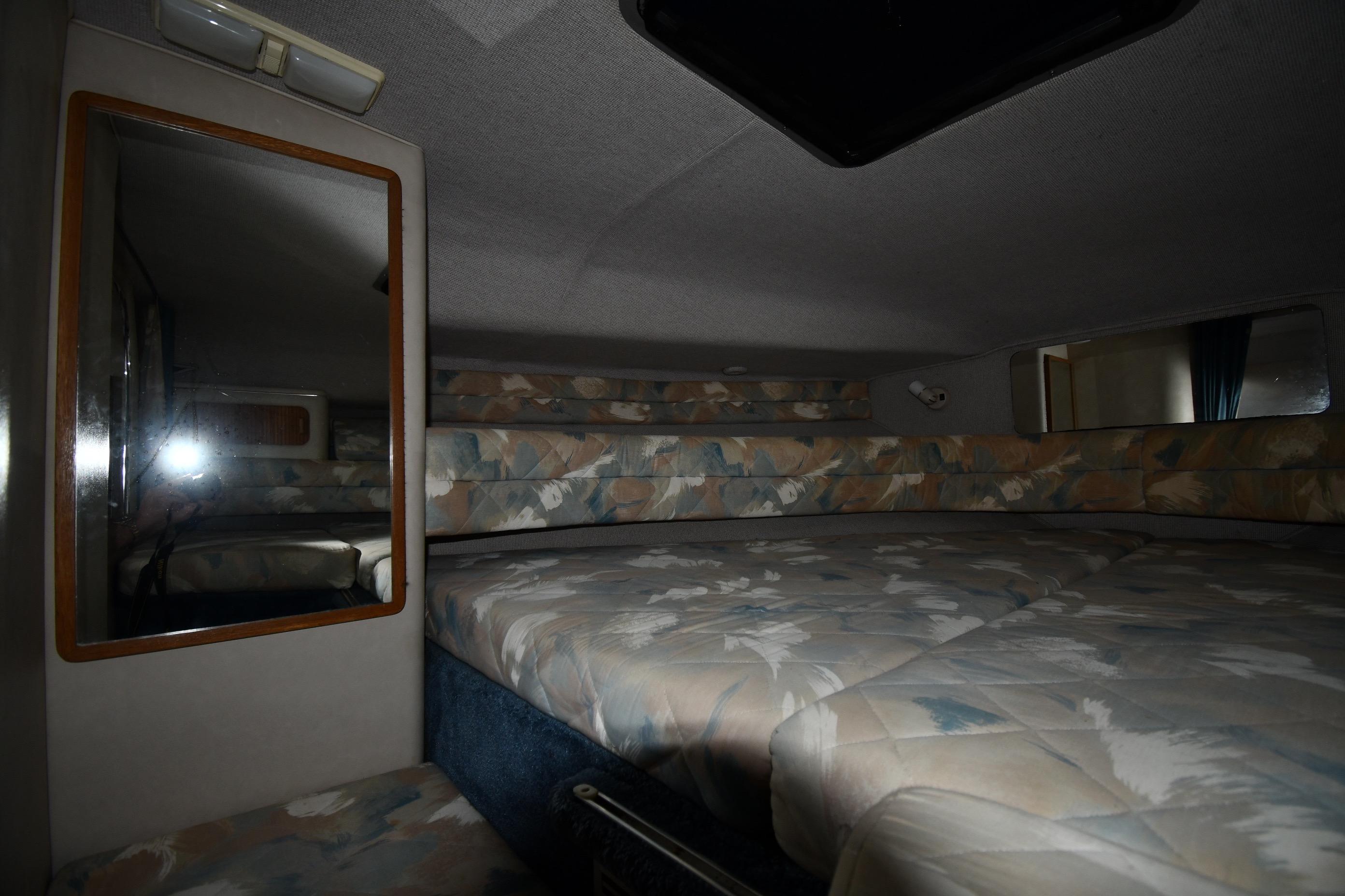 Interior cabin of 1993 Sea Ray 300 Sundancer with patterned bedding and mirror.