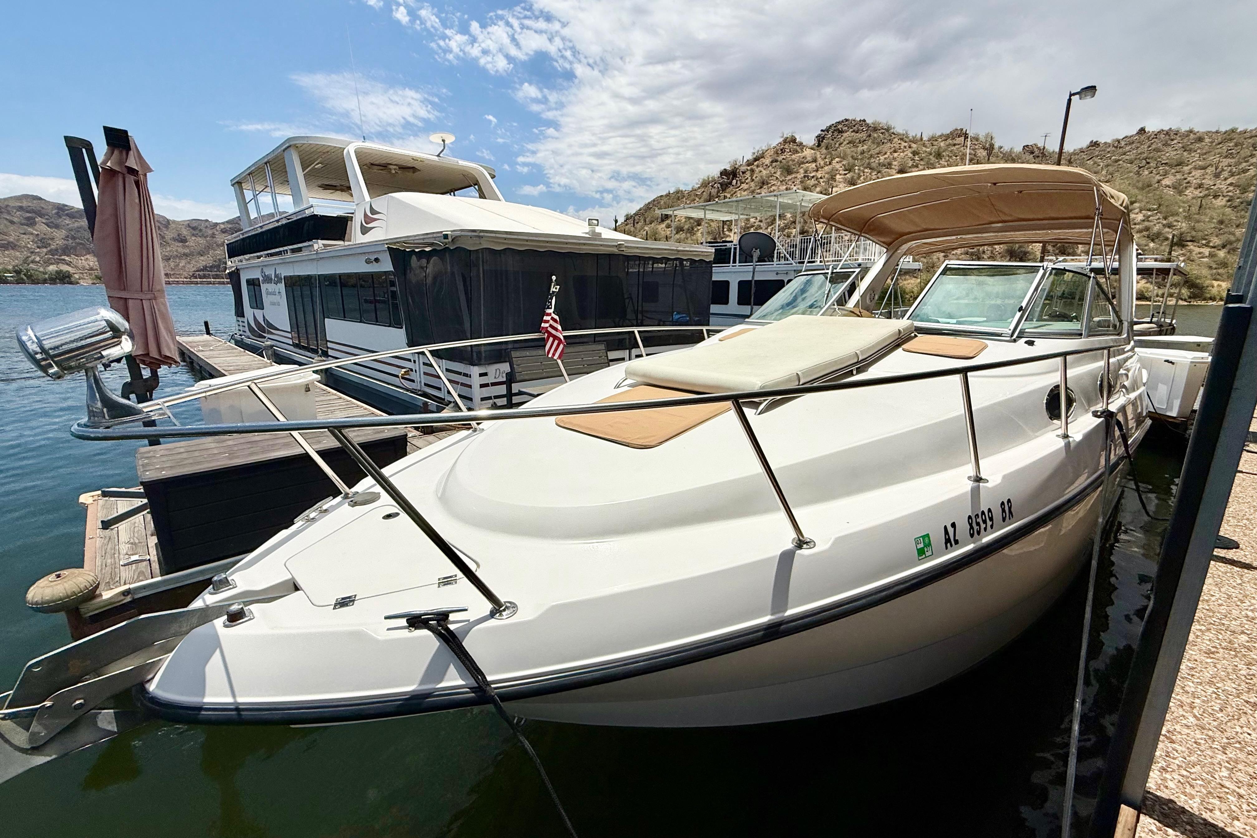 1999 Chaparral Signature 300 boat docked beside a larger vessel on a sunny day.