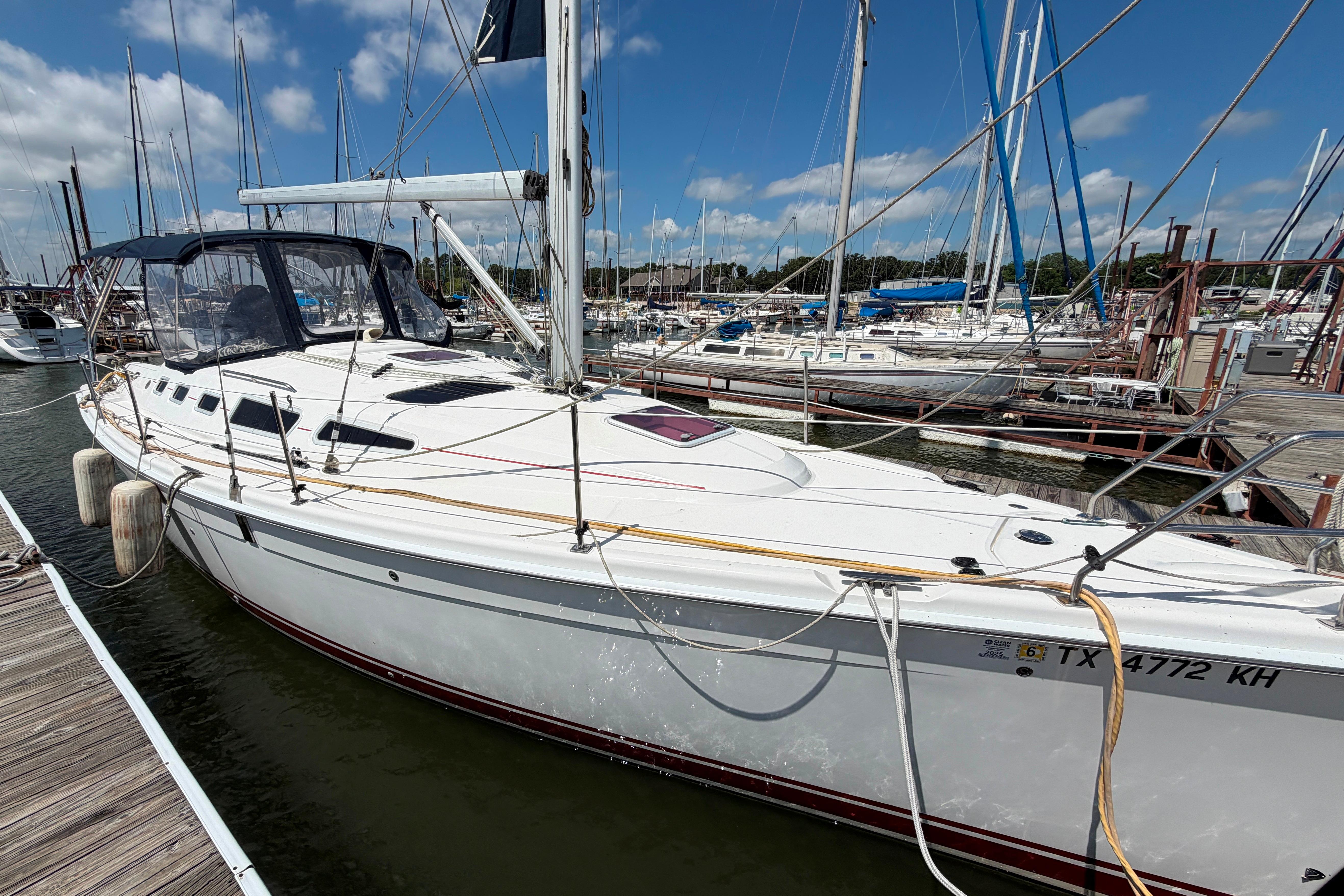 Sailboat docked at marina, Hunter 38 model, 2005, under clear blue sky.