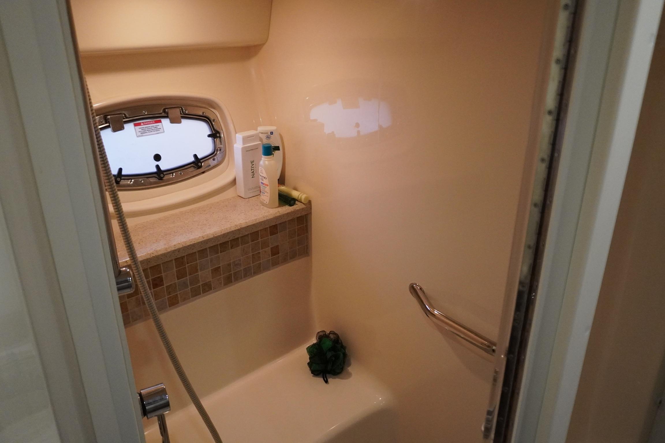 Shower area in 2009 Sea Ray 47 Sedan Bridge yacht with porthole and toiletries.