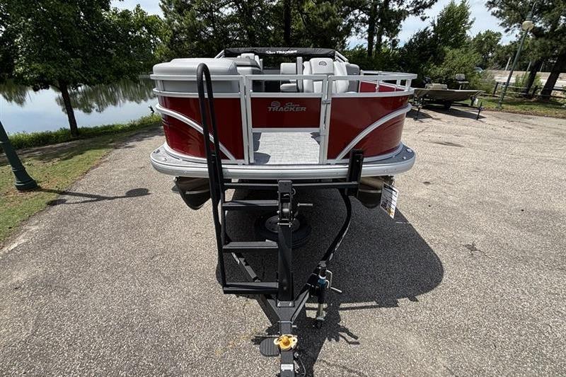 2026 Sun Tracker SportFish 20 DLX pontoon boat on trailer, parked near a lake.