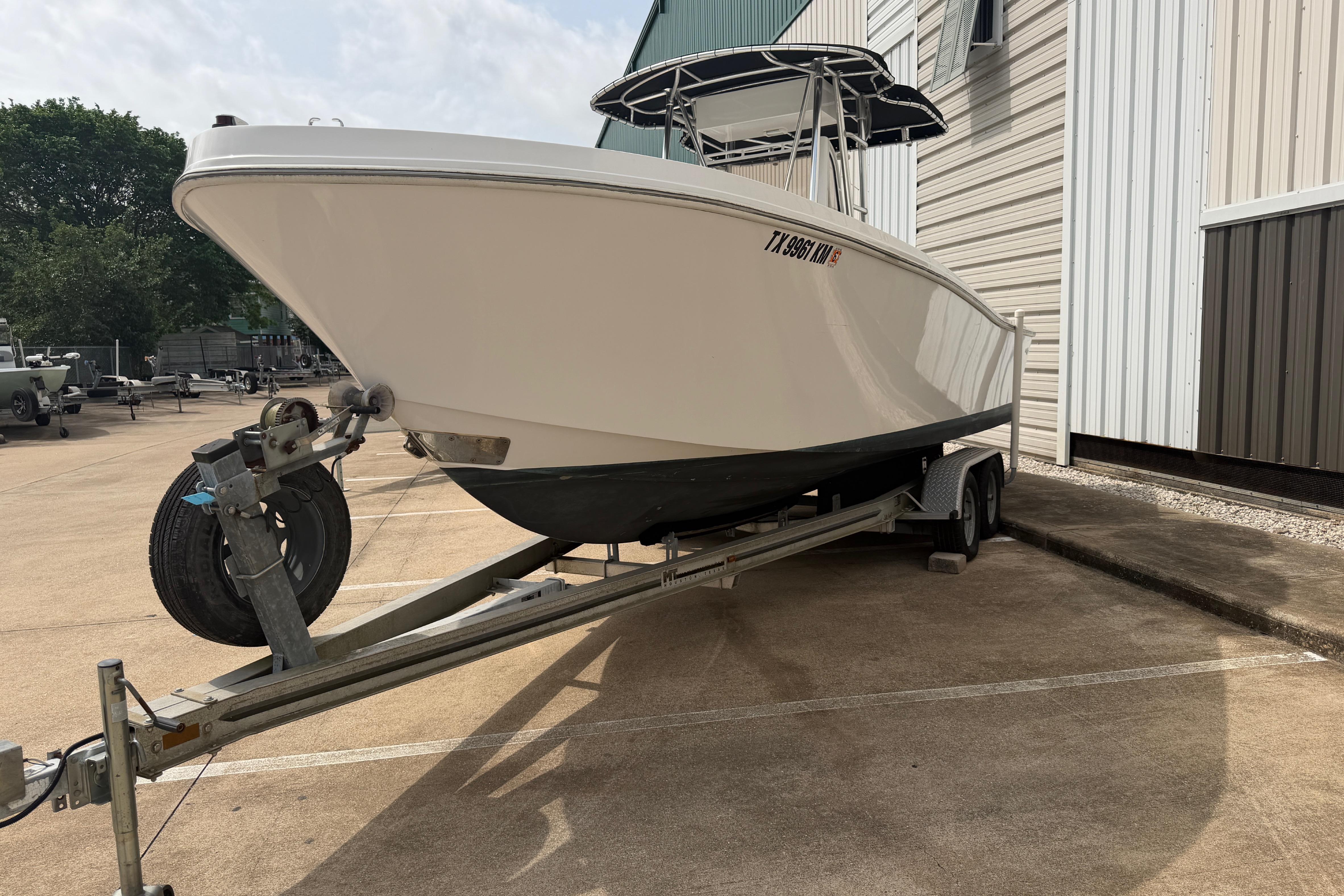 1990 Mako 241 Center Console boat on trailer, parked beside a building.