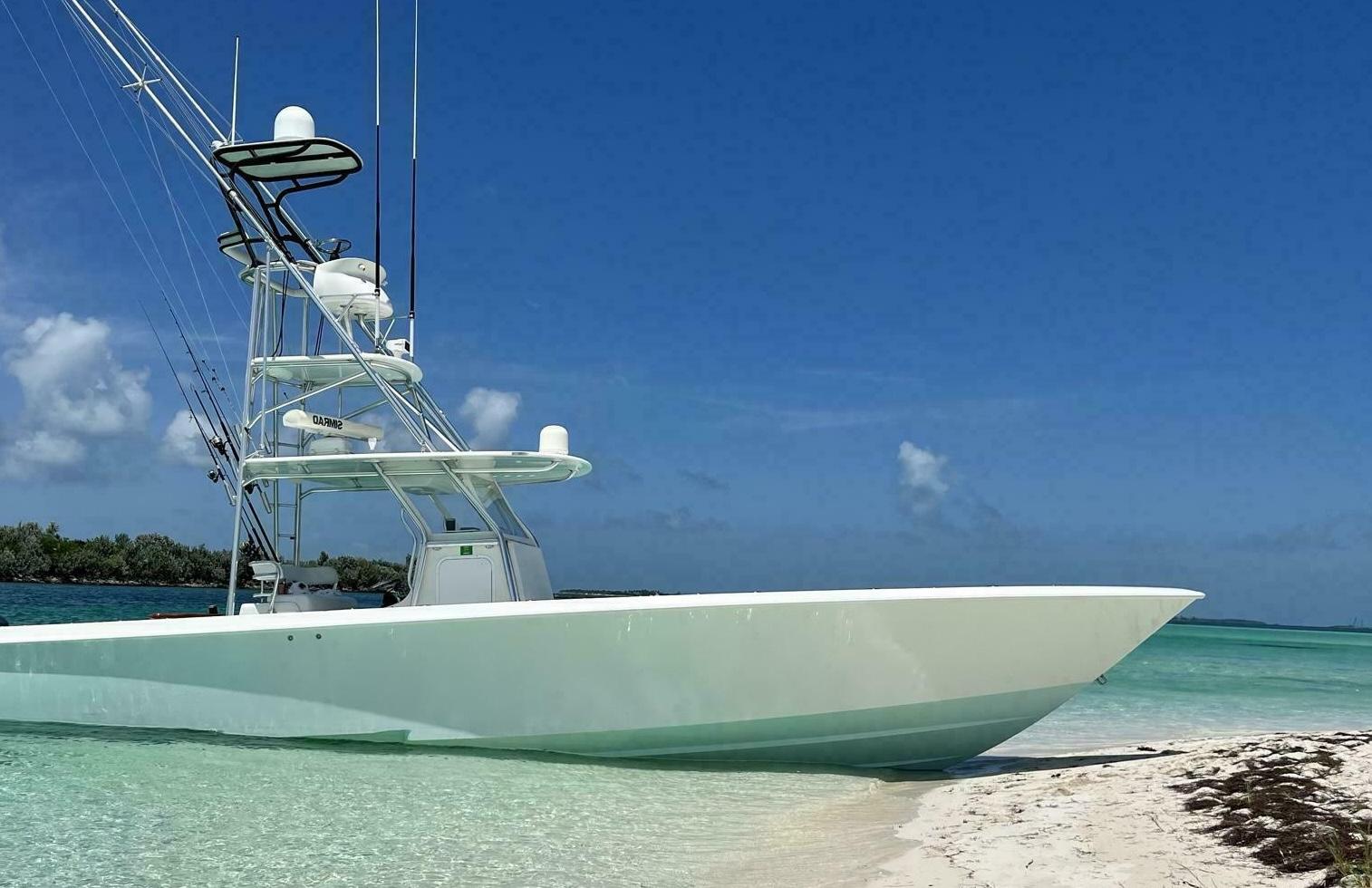 2012 Contender 39ST boat anchored on a sandy beach with clear blue skies.