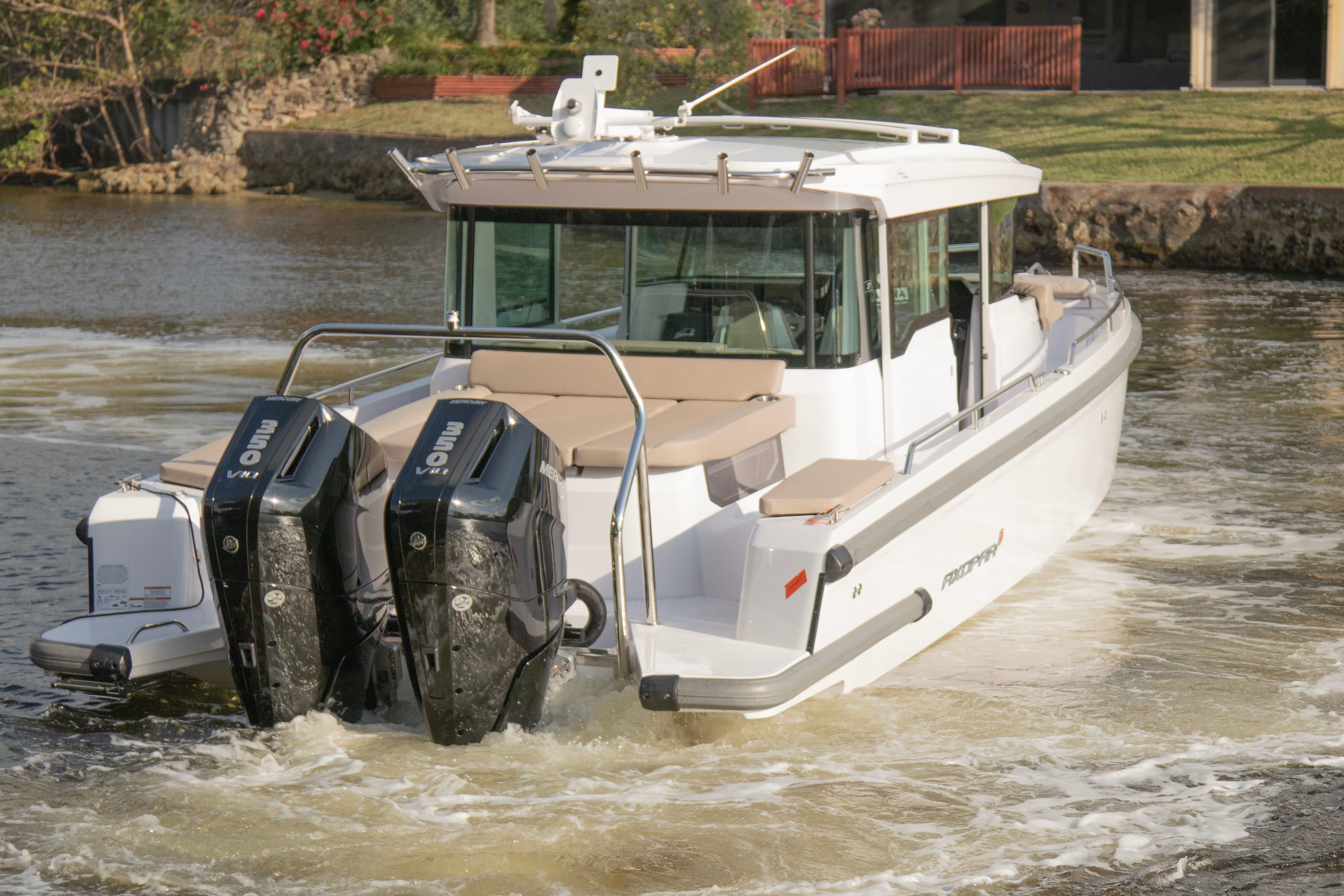 2024 Axopar 37XC CROSS CABIN boat with dual outboard engines on a calm waterway.