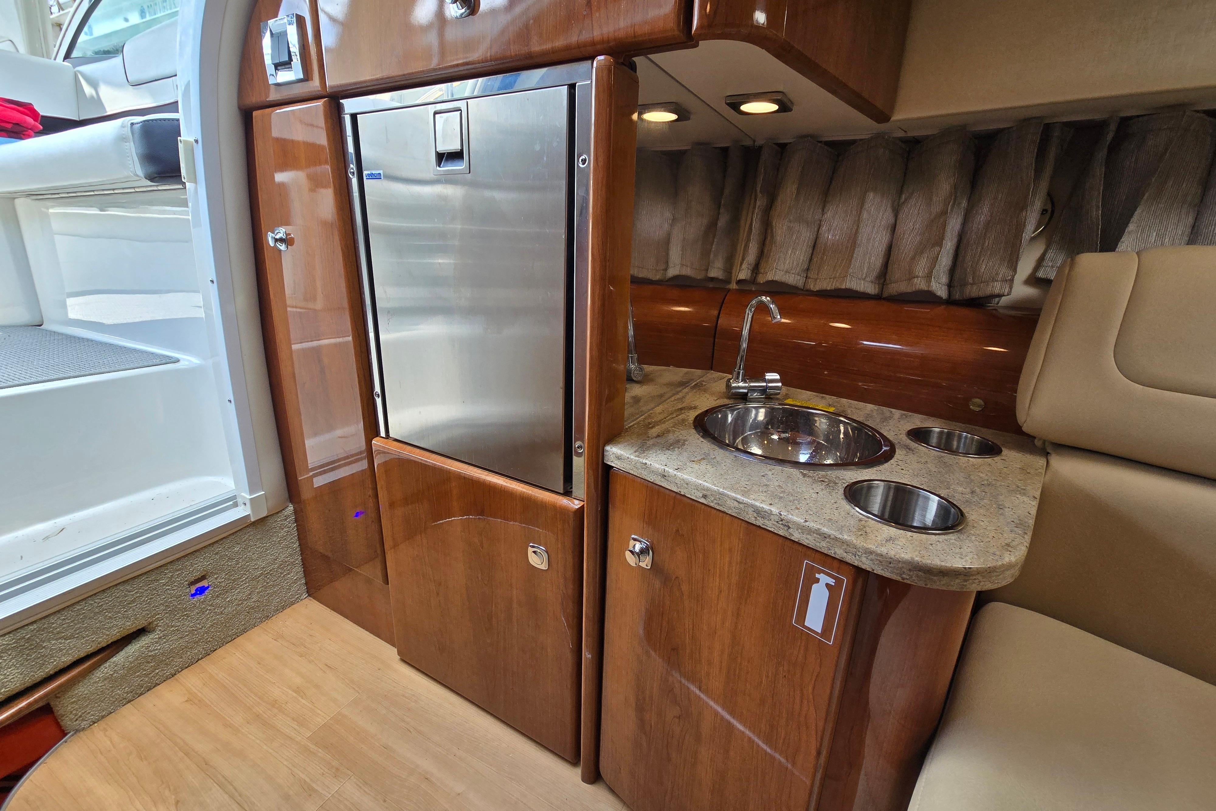 2017 Formula 310 Sun Sport interior with kitchenette, featuring sink and stainless steel fridge.
