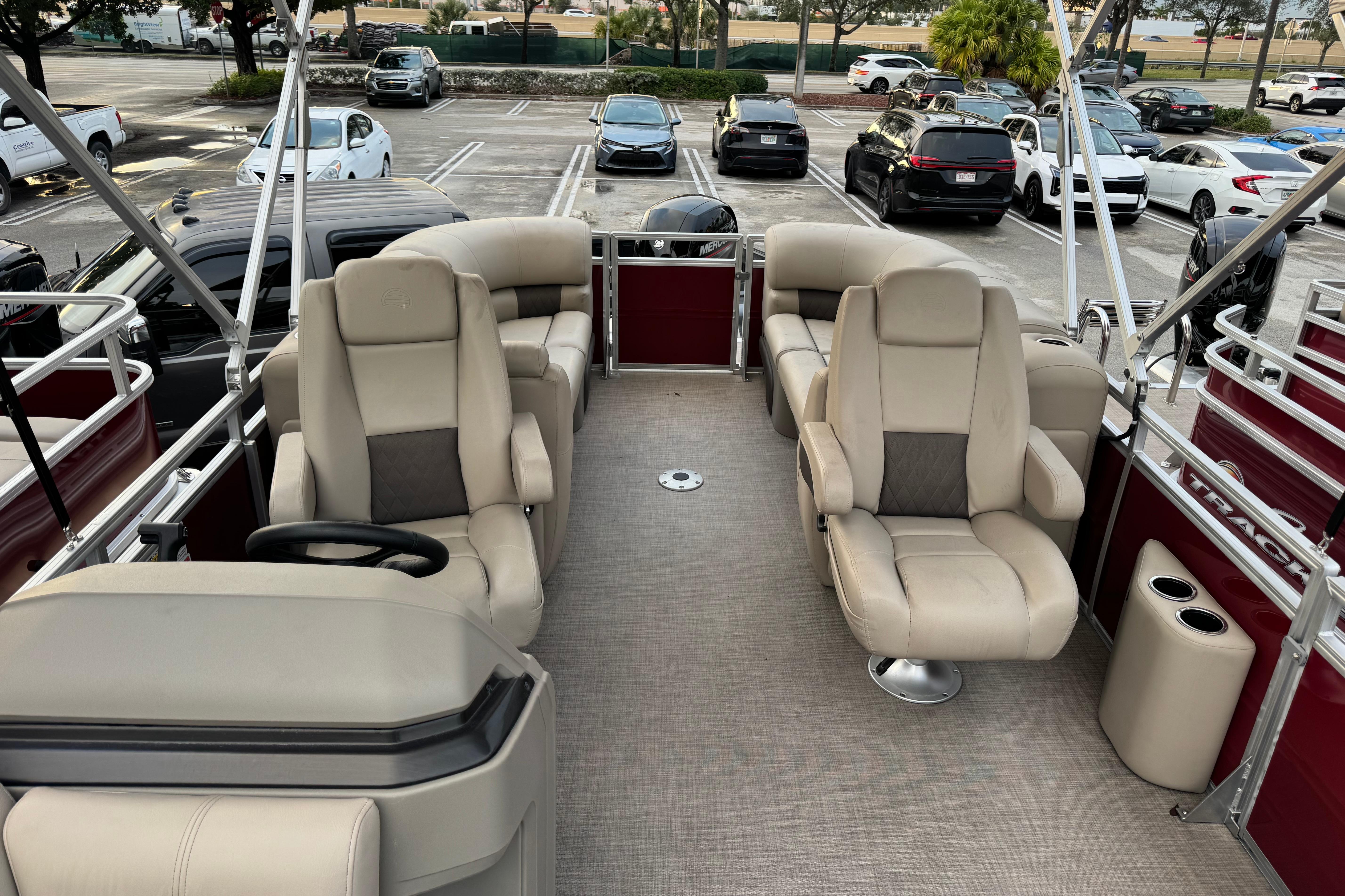 2025 Sun Tracker Party Barge 22 DLX interior with plush seating in a parking lot.