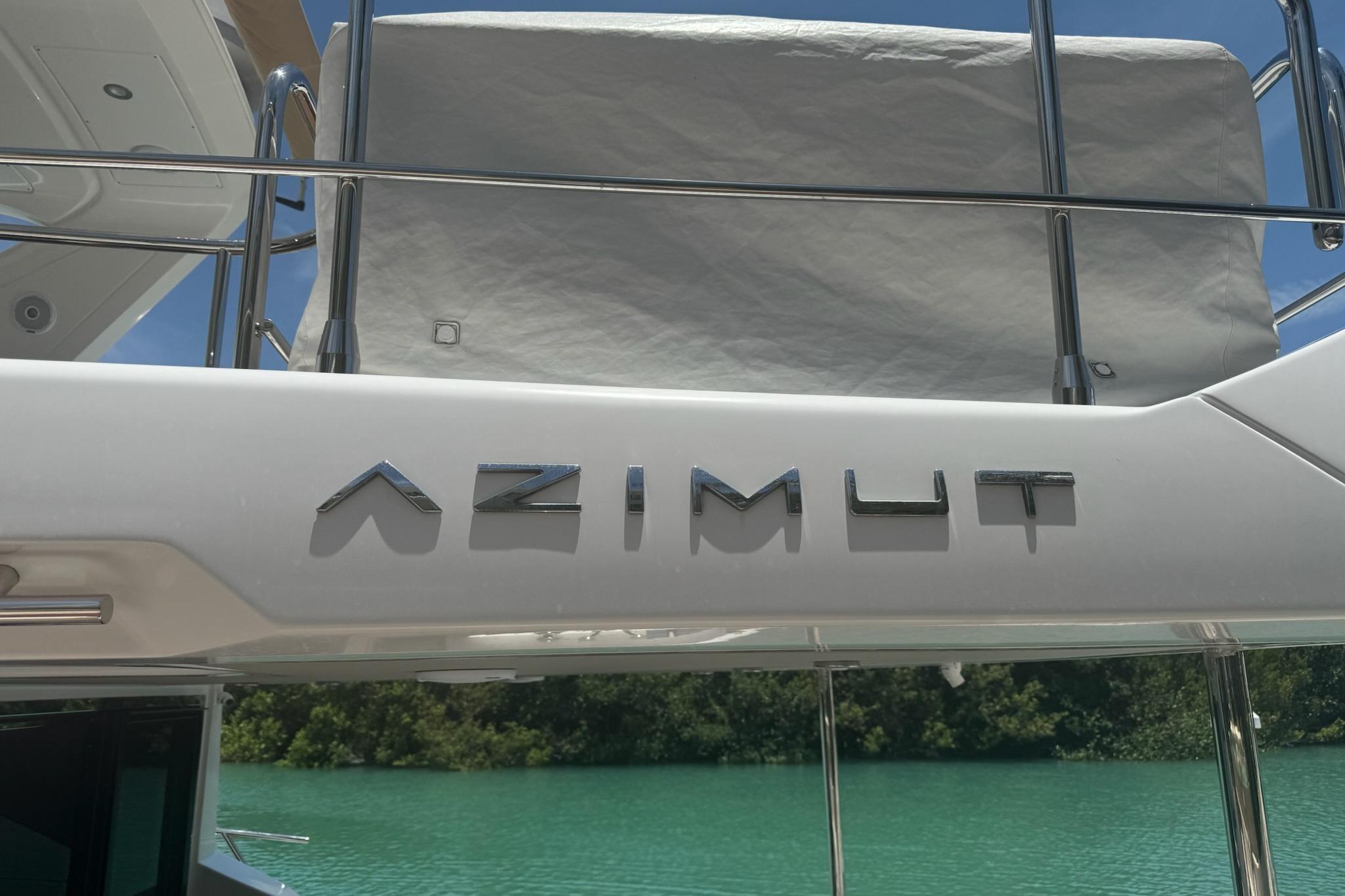 Azimut 55 yacht, 2021 model, with sleek design and chrome lettering, docked by turquoise water.