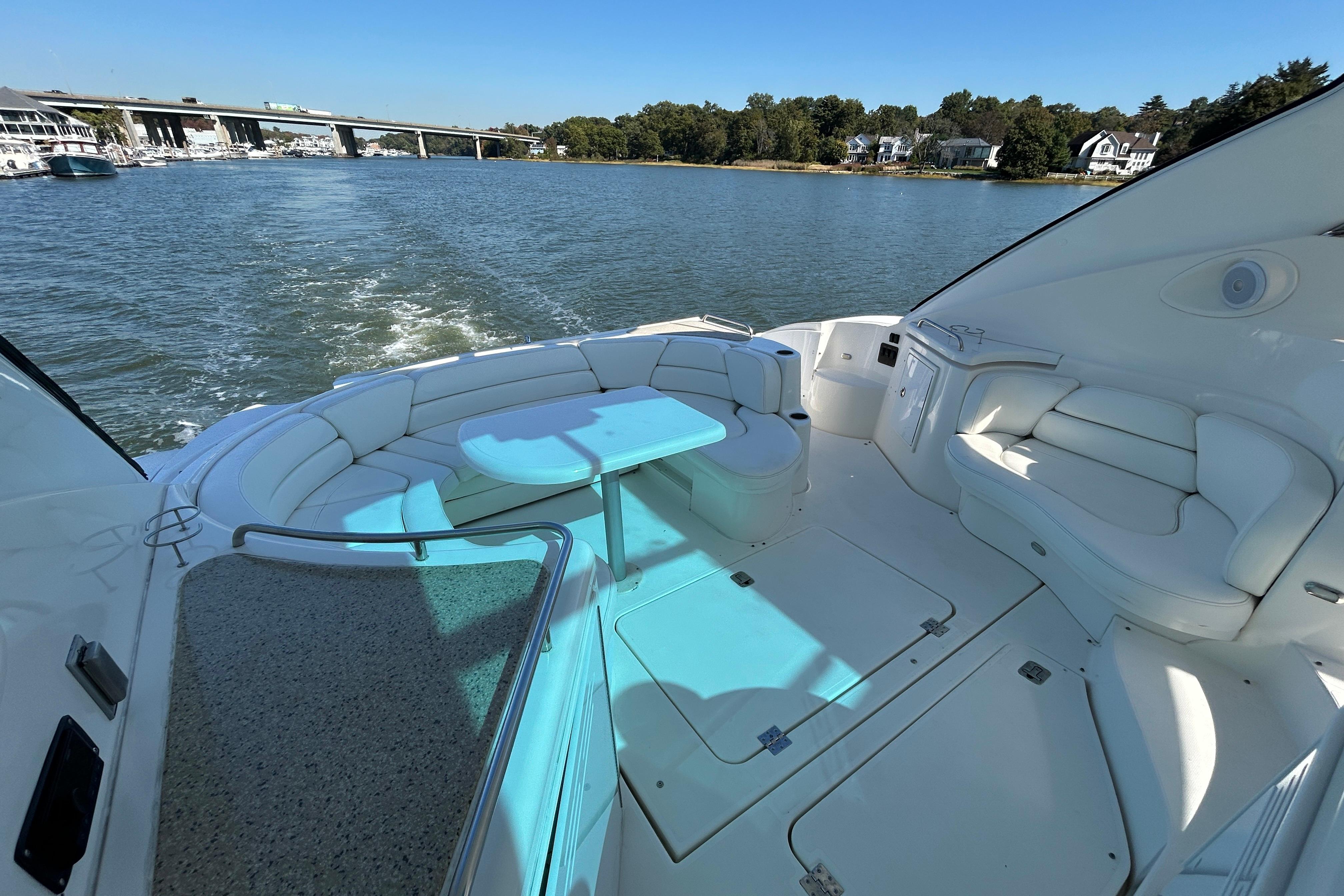 2003 Cruisers Yachts 540 Express, spacious deck with seating, cruising on a scenic waterway.