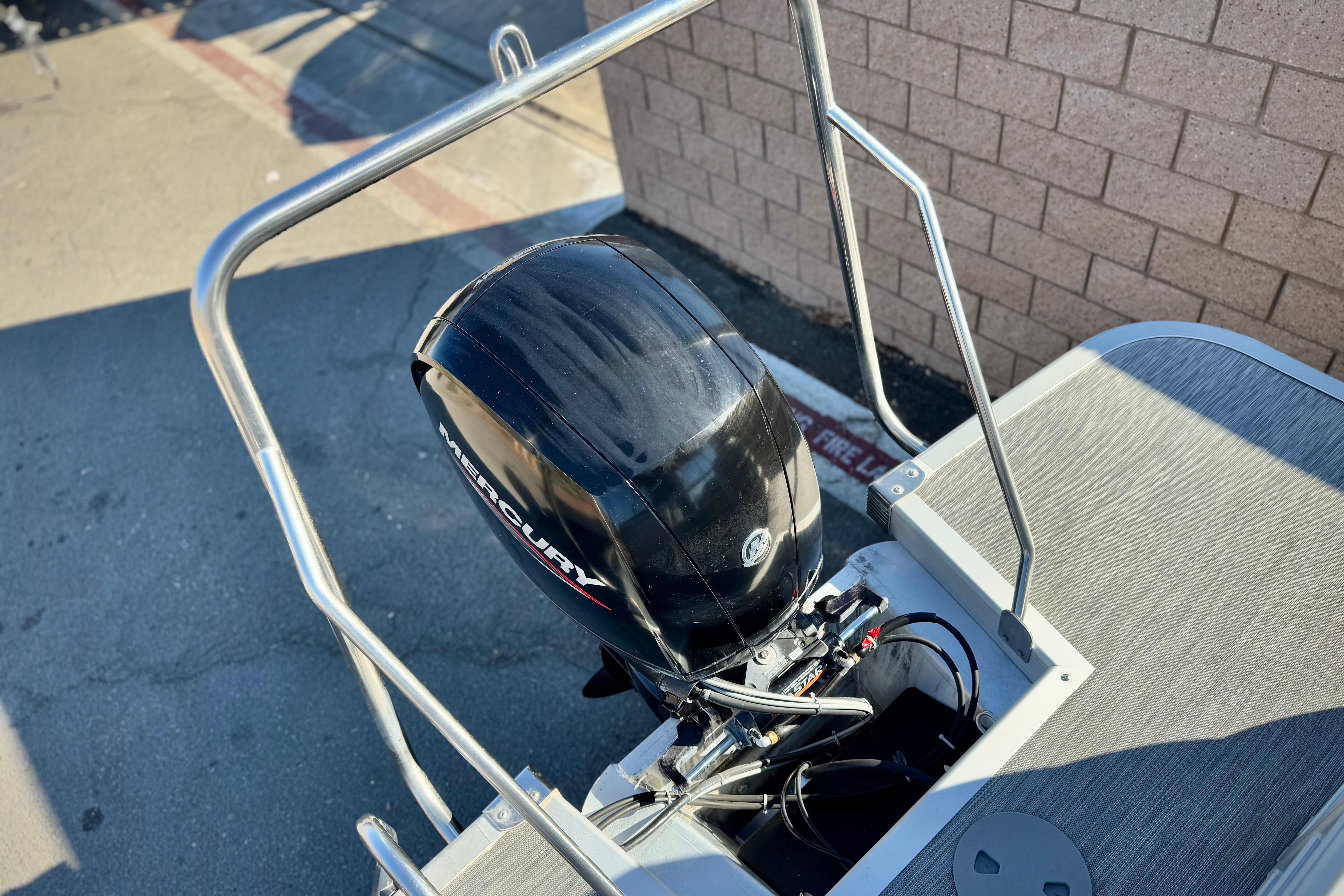 2021 Bennington 23LSR boat with Mercury outboard motor, docked near a brick wall.