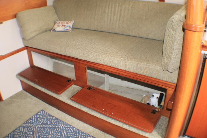 1988 Tollycraft 30 Sport Cruiser interior with cushioned seating and wooden storage compartments.
