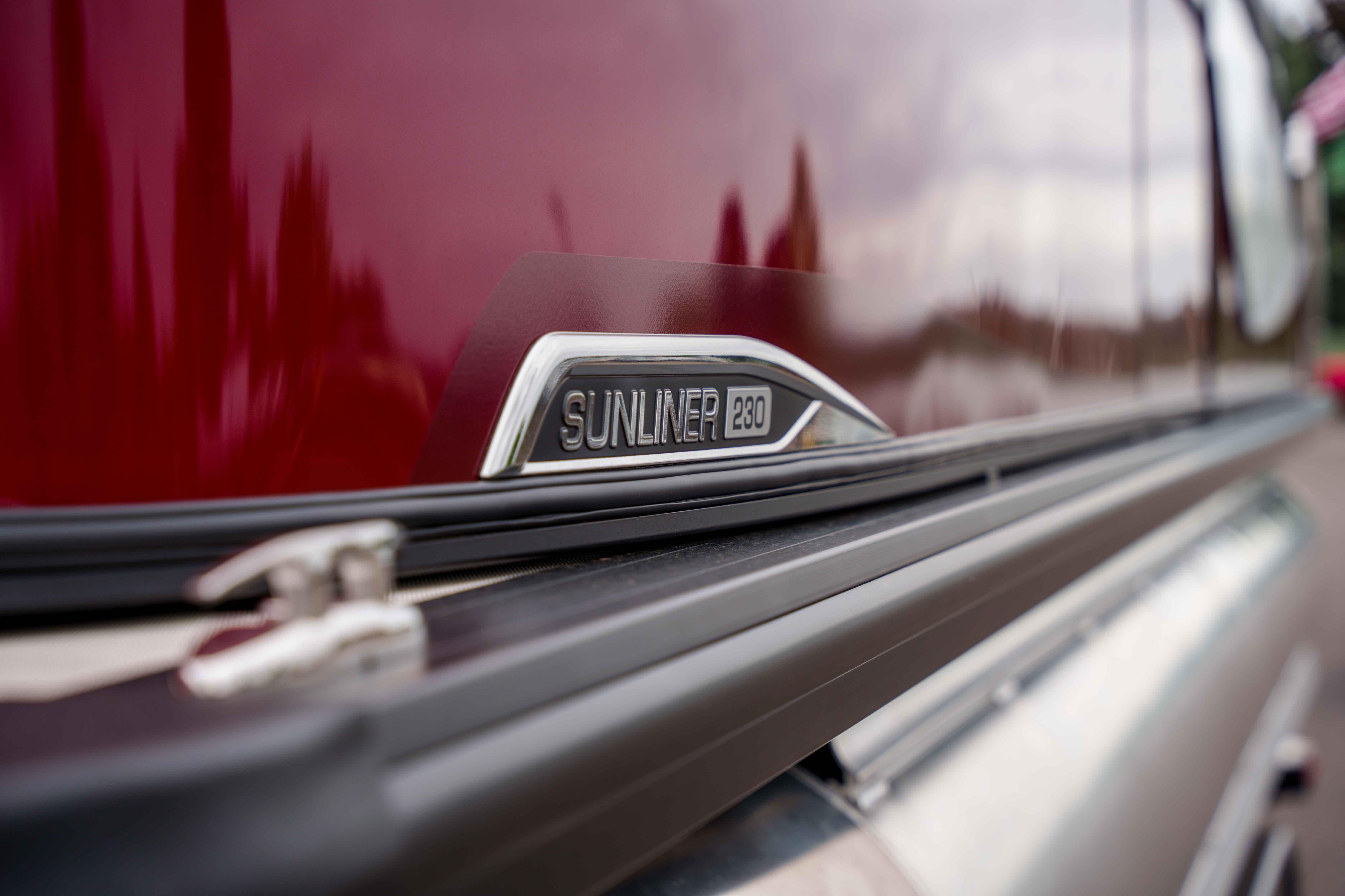 2026 Harris Sunliner 230 emblem on a sleek, reflective red surface.