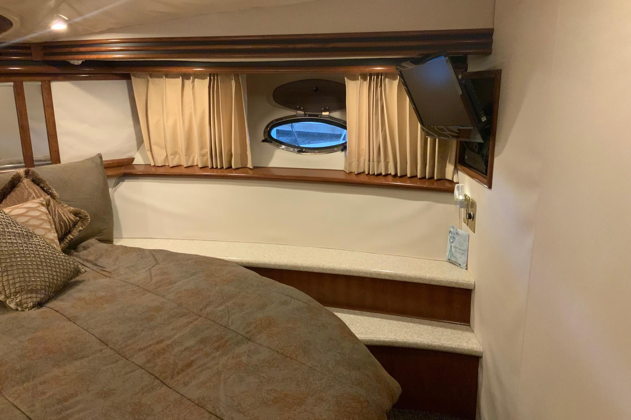 Interior of 1999 Carver 450 Voyager Pilothouse with bed, porthole, and TV.