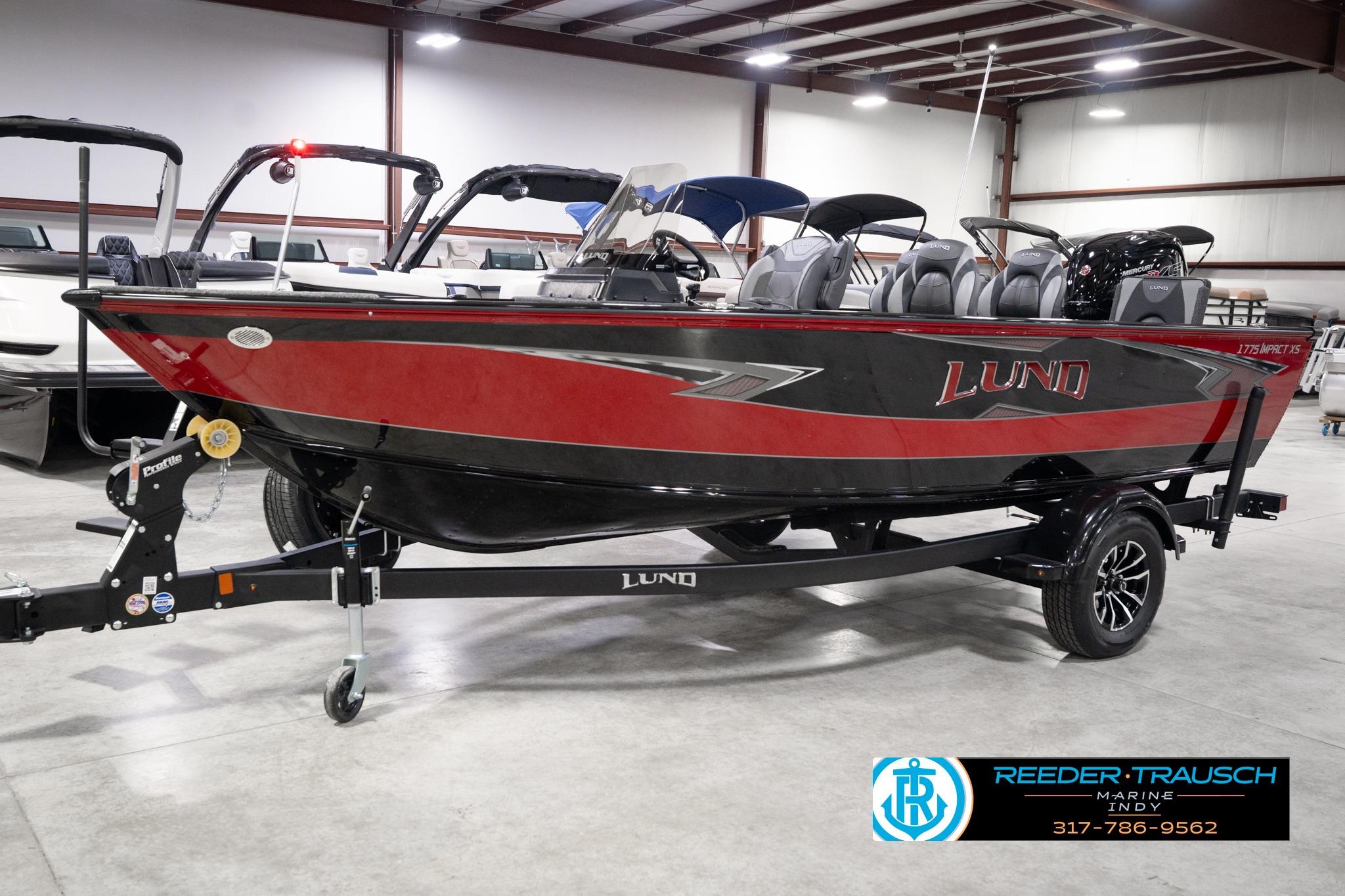 2026 Lund 1775 Impact XS SS boat in showroom, red and black design, on trailer.