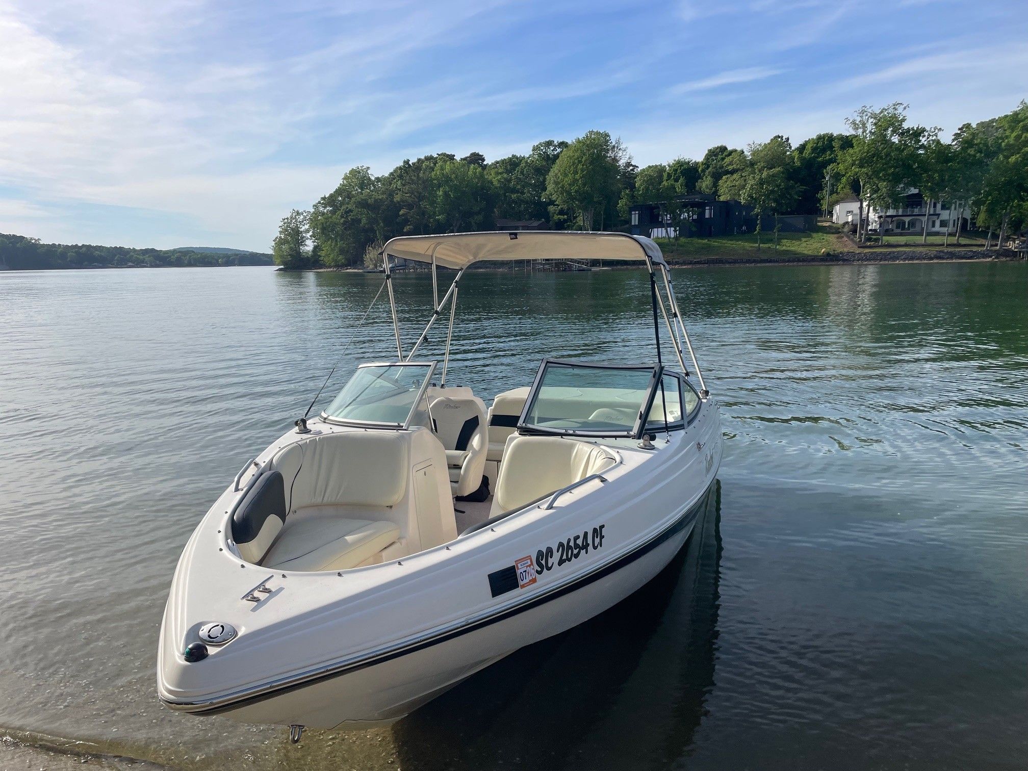 2002 Rinker 212 Captiva Bowrider on calm lake under sunny skies.