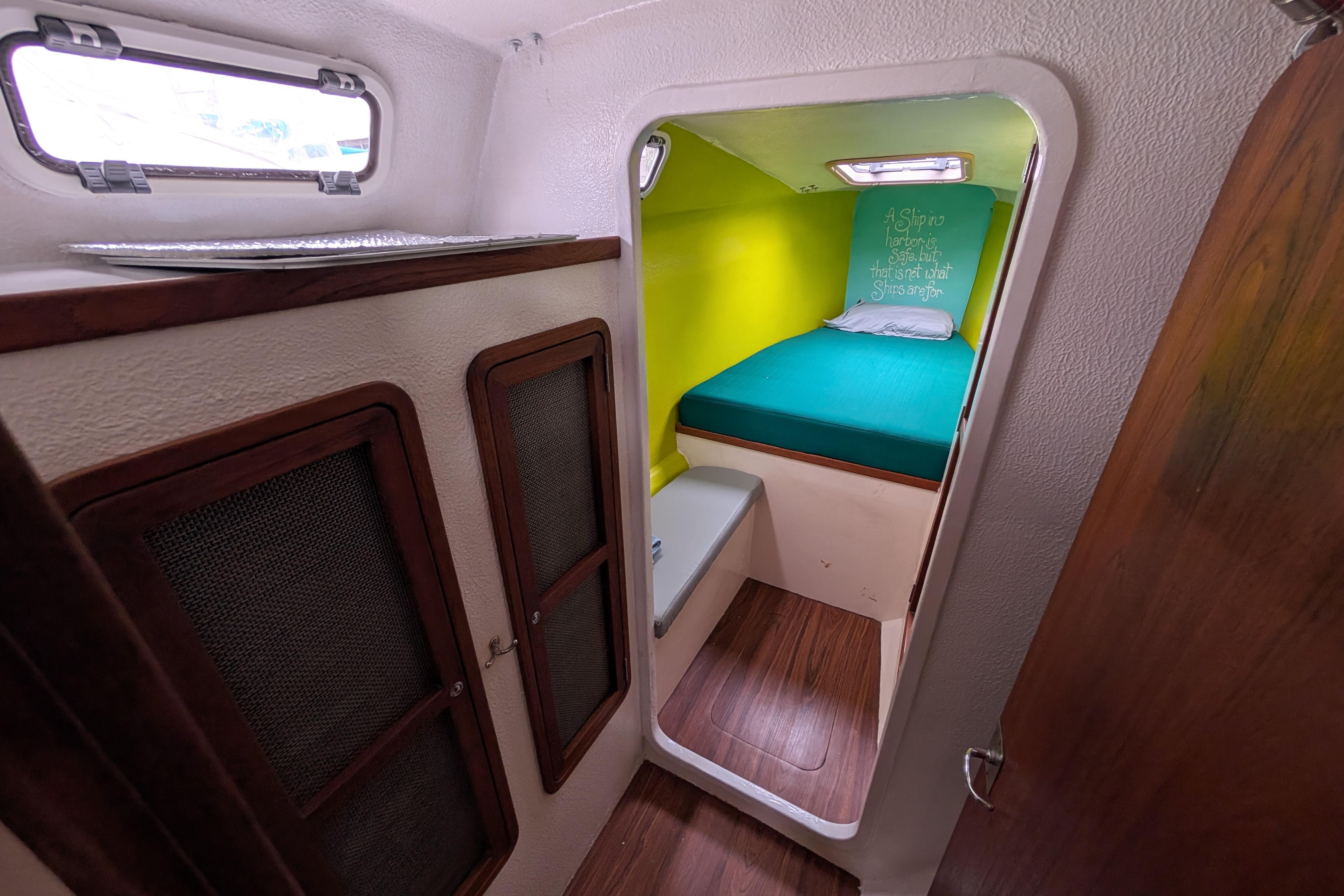 Cozy cabin interior of 1999 Island Spirit 37 sailboat with vibrant bedding and wooden accents.