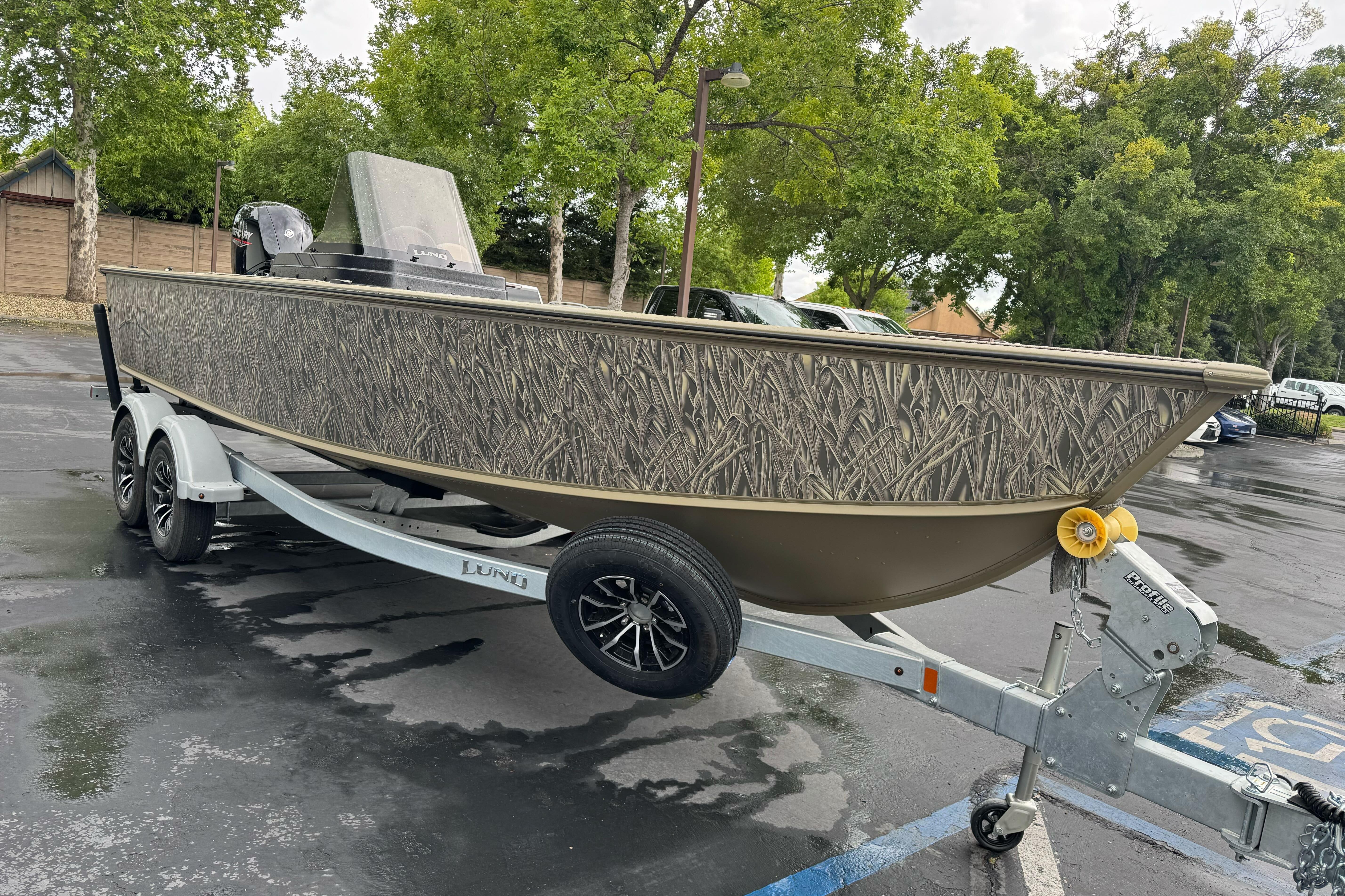 2026 Lund 2075 Alaskan SS boat on trailer, parked outdoors with tree background.