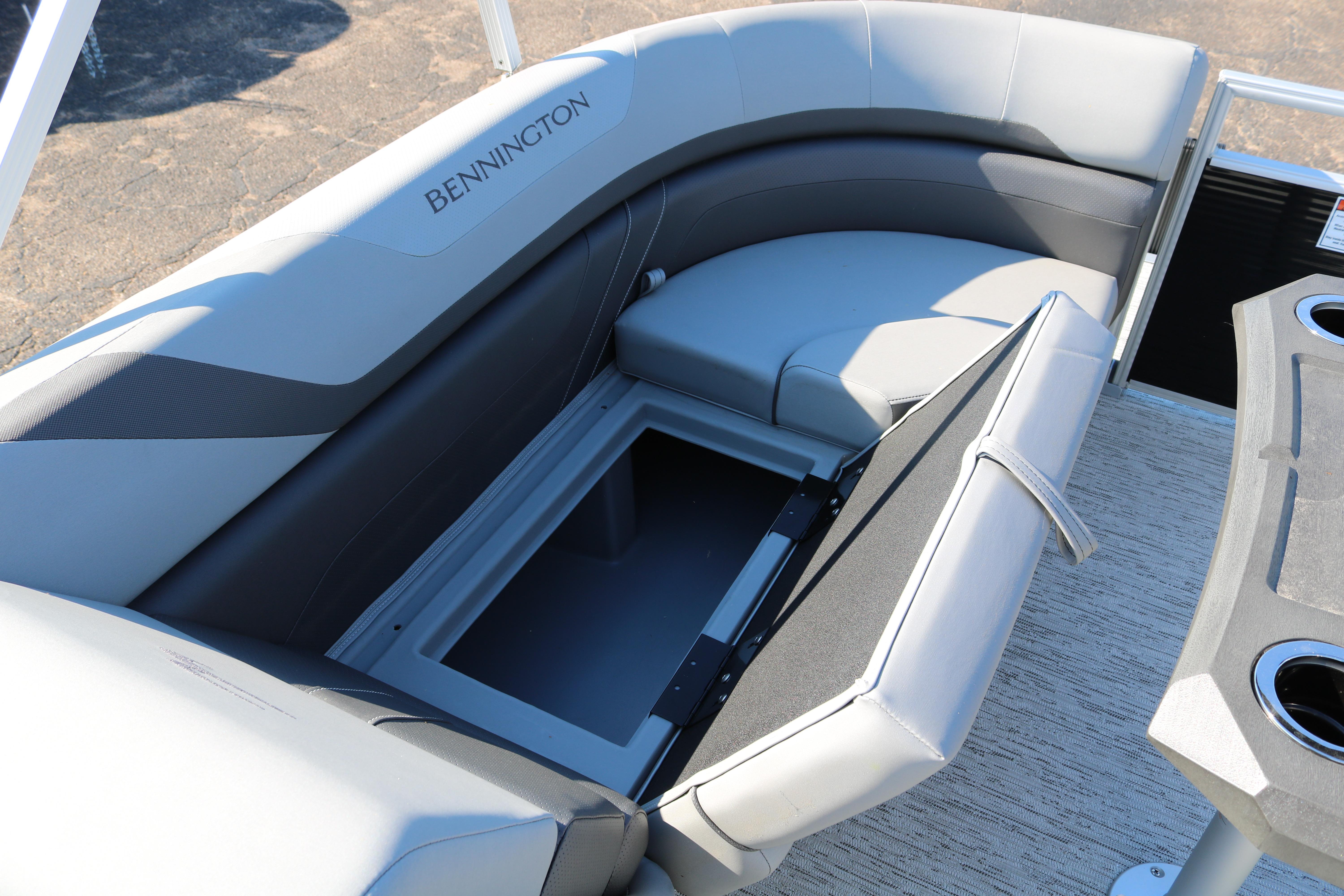2026 Bennington 22SX Stern Radius boat with open storage compartment and cushioned seating.