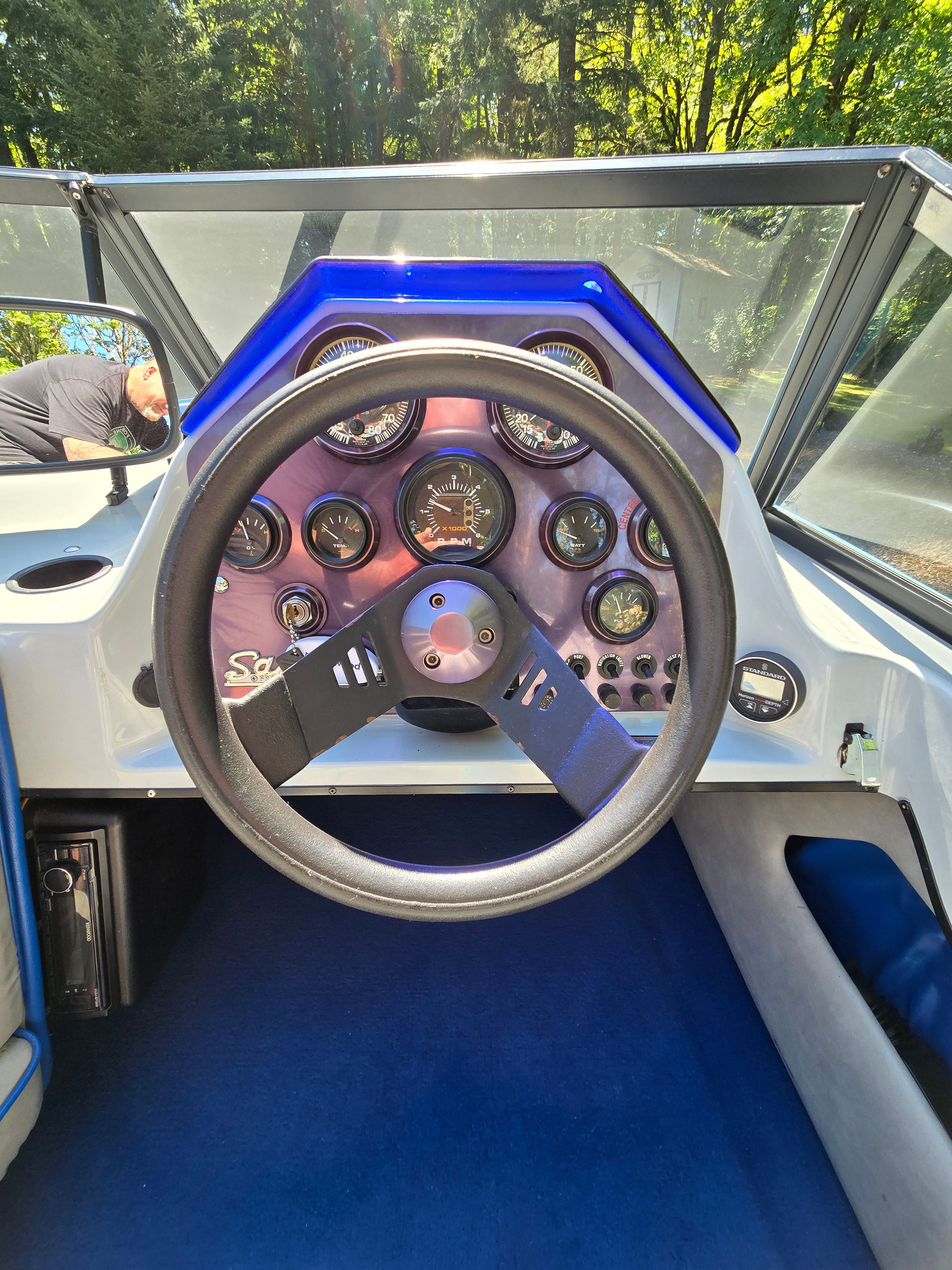 The image shows the cockpit of a 1990 Ski Sanger boat with a modern steering wheel and instruments.