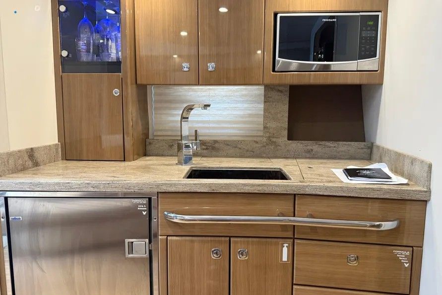 Galley with wooden cabinets, sink, microwave, and refrigerator.