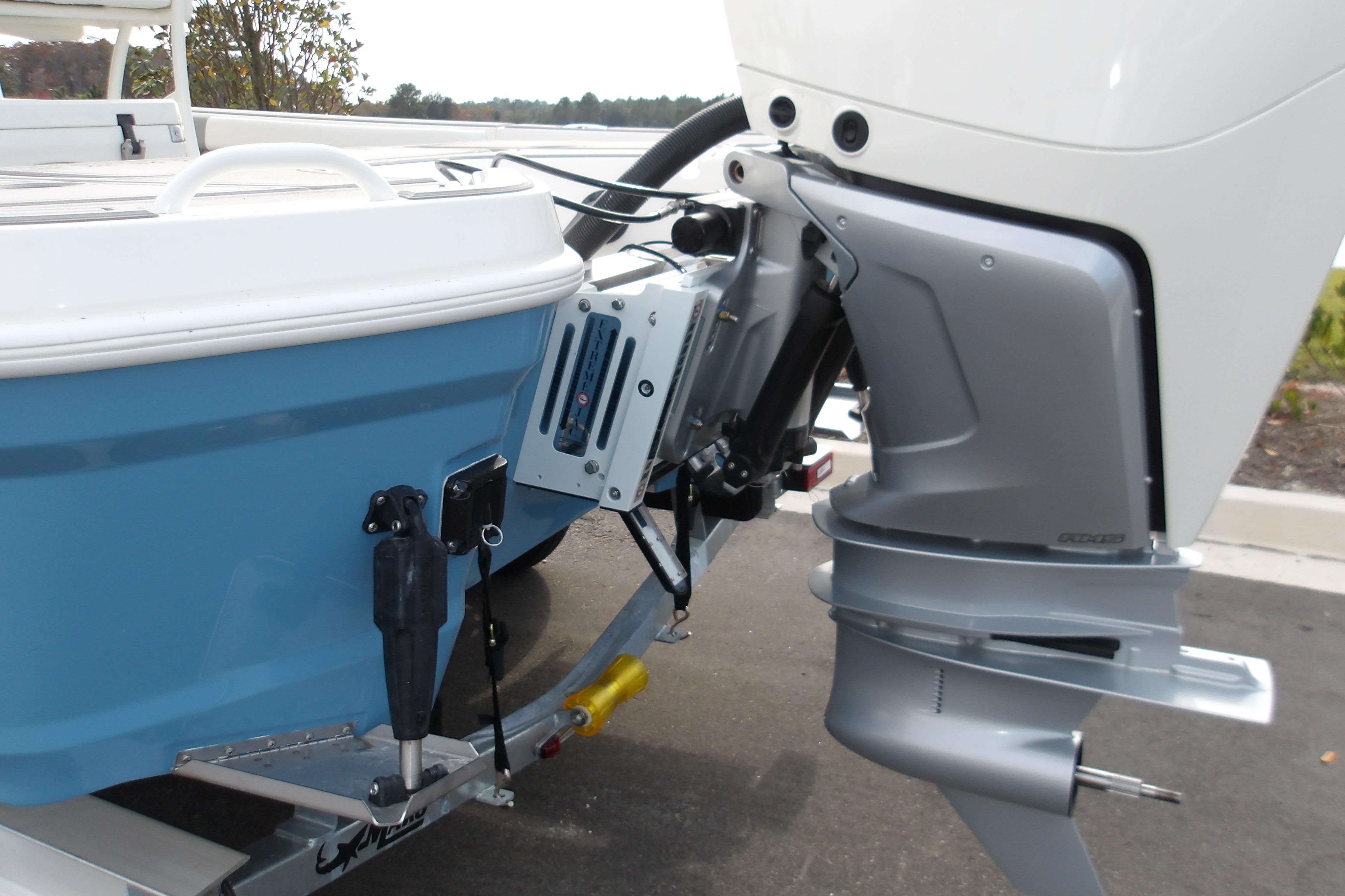 2026 Mako 24 APEX boat with outboard motor, blue hull, and trailer.